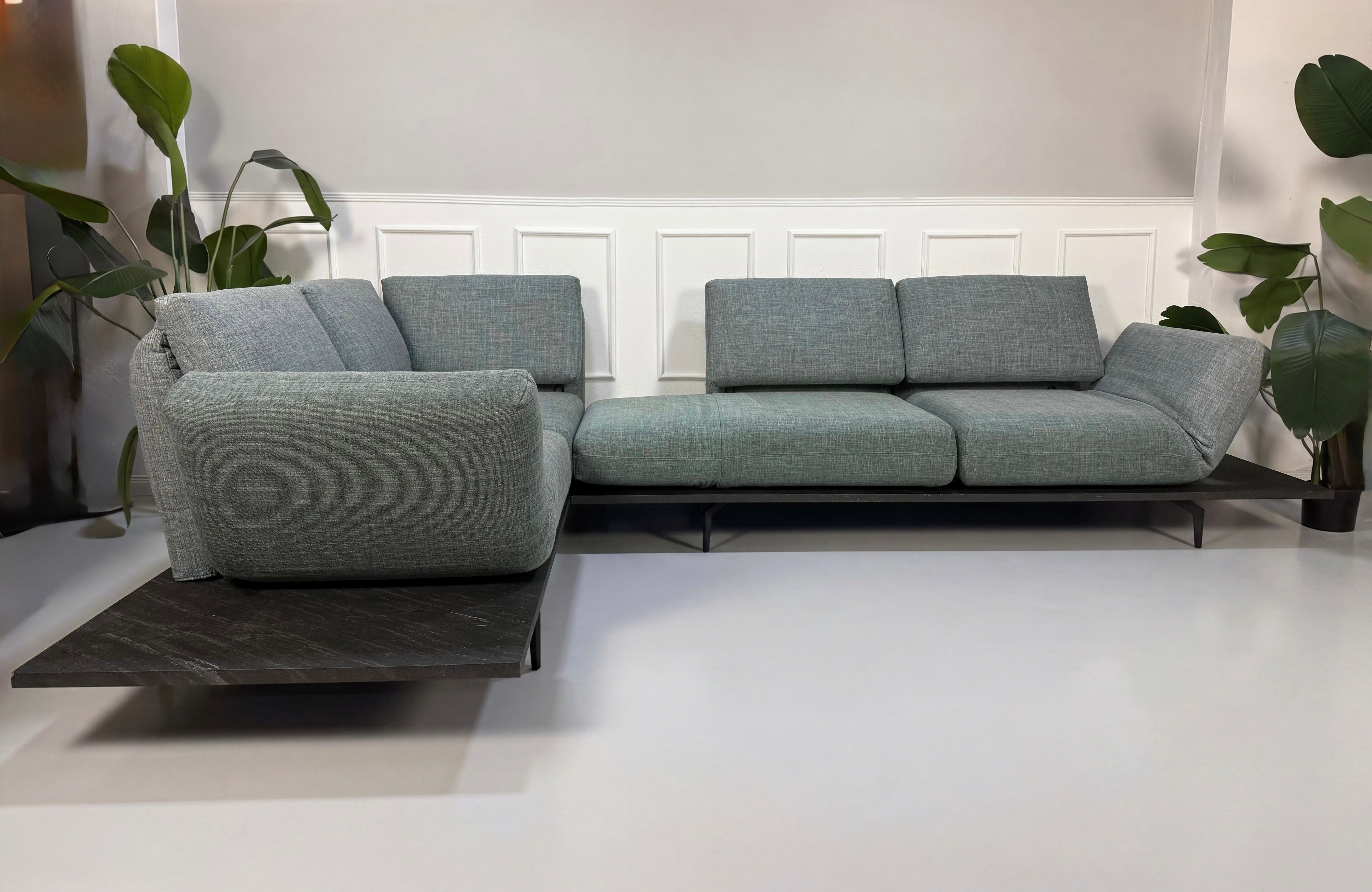 Gebrauchtes blau graues Rolf Benz Aura Designer Stoff Sofa vor einer Wand, stilvoll und modern eingerichtet.