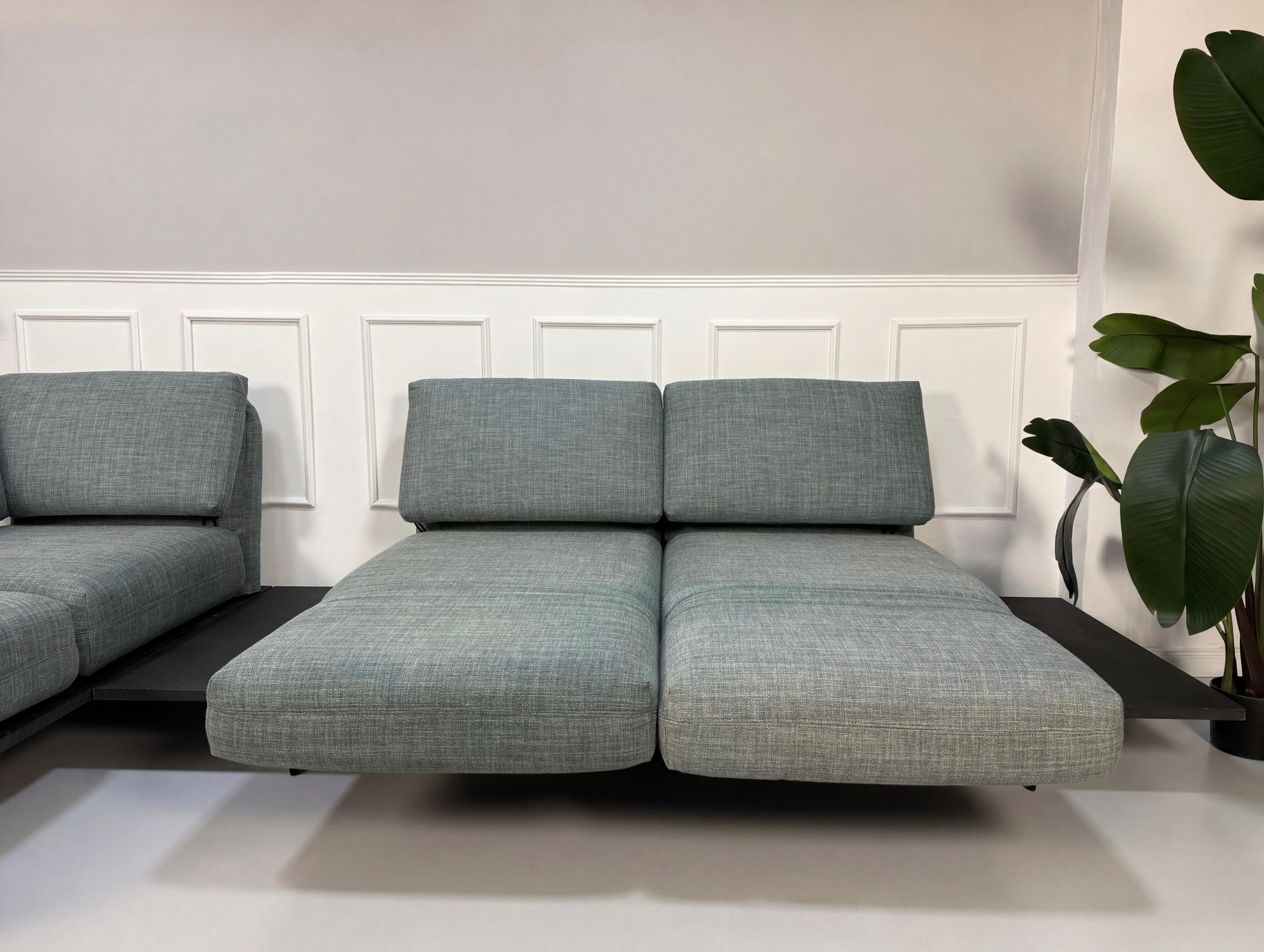 Gebrauchtes blau graues Rolf Benz Aura Designer Stoff Sofa vor einer Wand, stilvoll und modern eingerichtet.