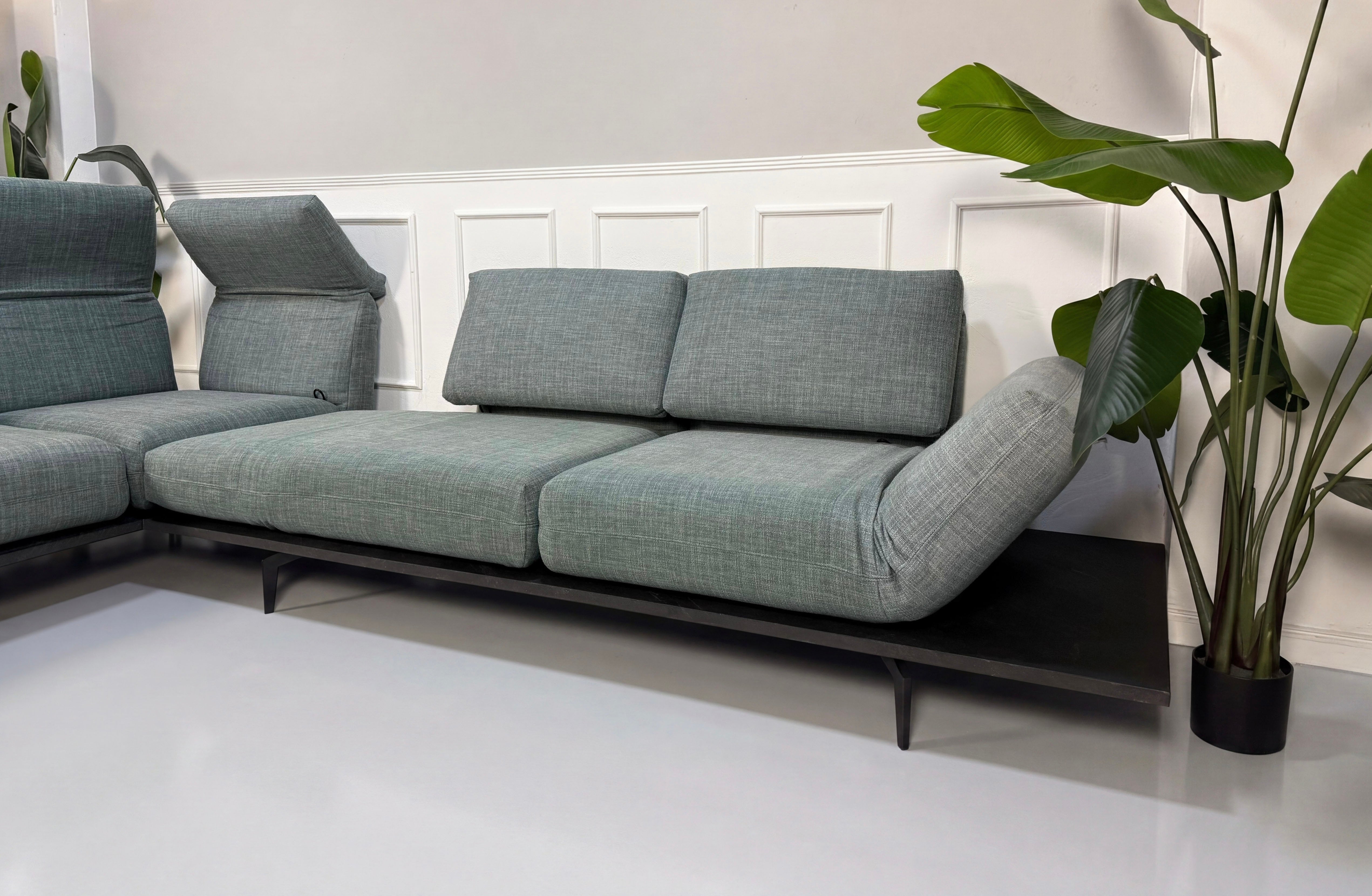 Gebrauchtes blau graues Rolf Benz Aura Designer Stoff Sofa vor einer Wand, stilvoll und modern eingerichtet.