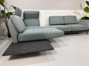 Gebrauchtes blau graues Rolf Benz Aura Designer Stoff Sofa vor einer Wand, stilvoll und modern eingerichtet.