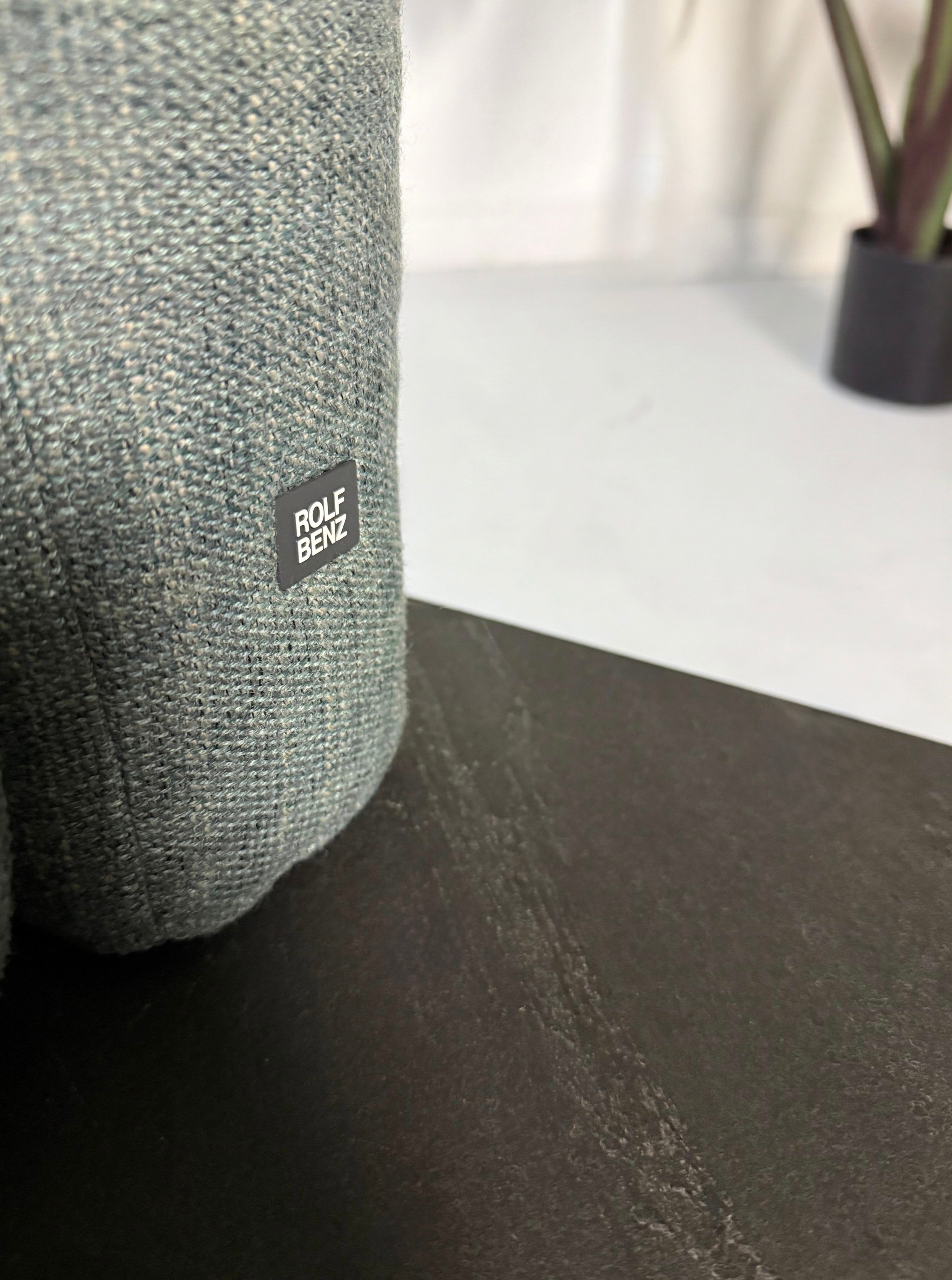 Gebrauchtes blau graues Rolf Benz Aura Designer Stoff Sofa vor einer Wand, stilvoll und modern eingerichtet.