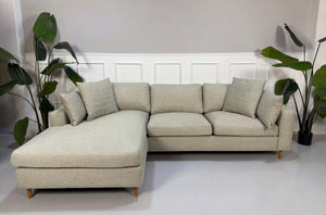 Gebrauchtes grau sand Bolia Scandinavia Designer Stoff Sofa vor einer Wand, stilvoll und modern eingerichtet.

