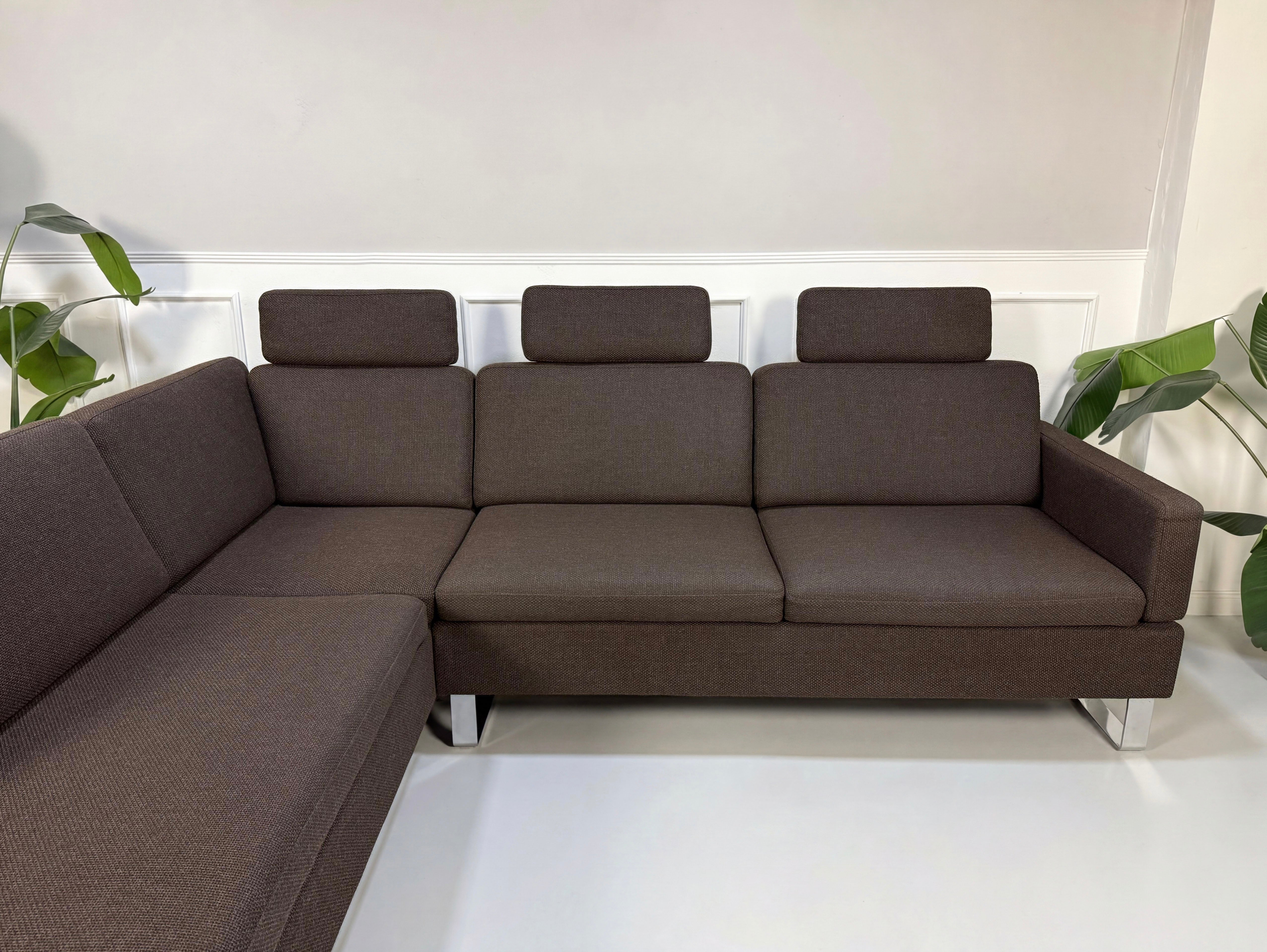 Gebrauchtes braunes Brühl Ecksofa Designer Stoff Sofa vor einer Wand, stilvoll und modern eingerichtet.