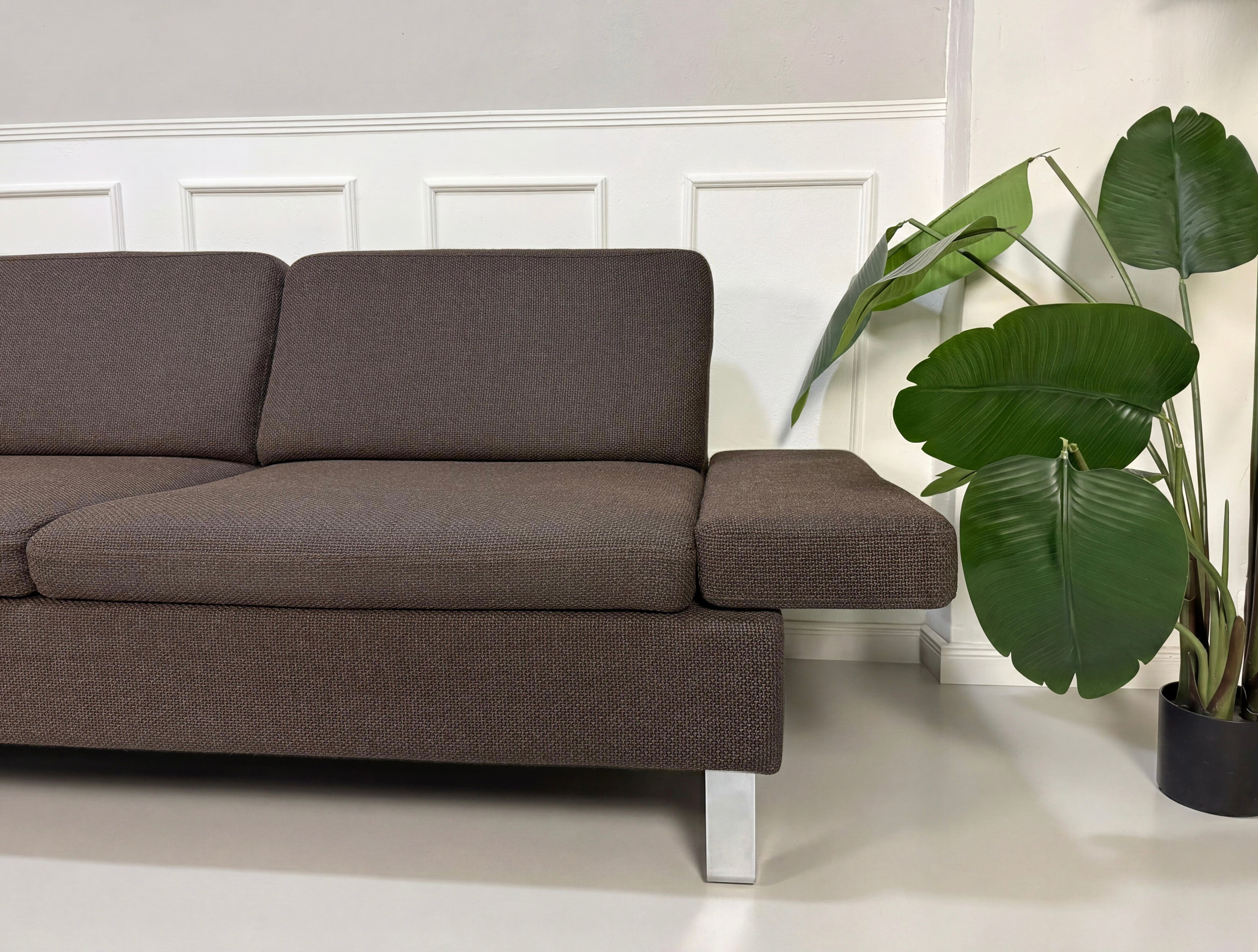 Gebrauchtes braunes Brühl Ecksofa Designer Stoff Sofa vor einer Wand, stilvoll und modern eingerichtet.