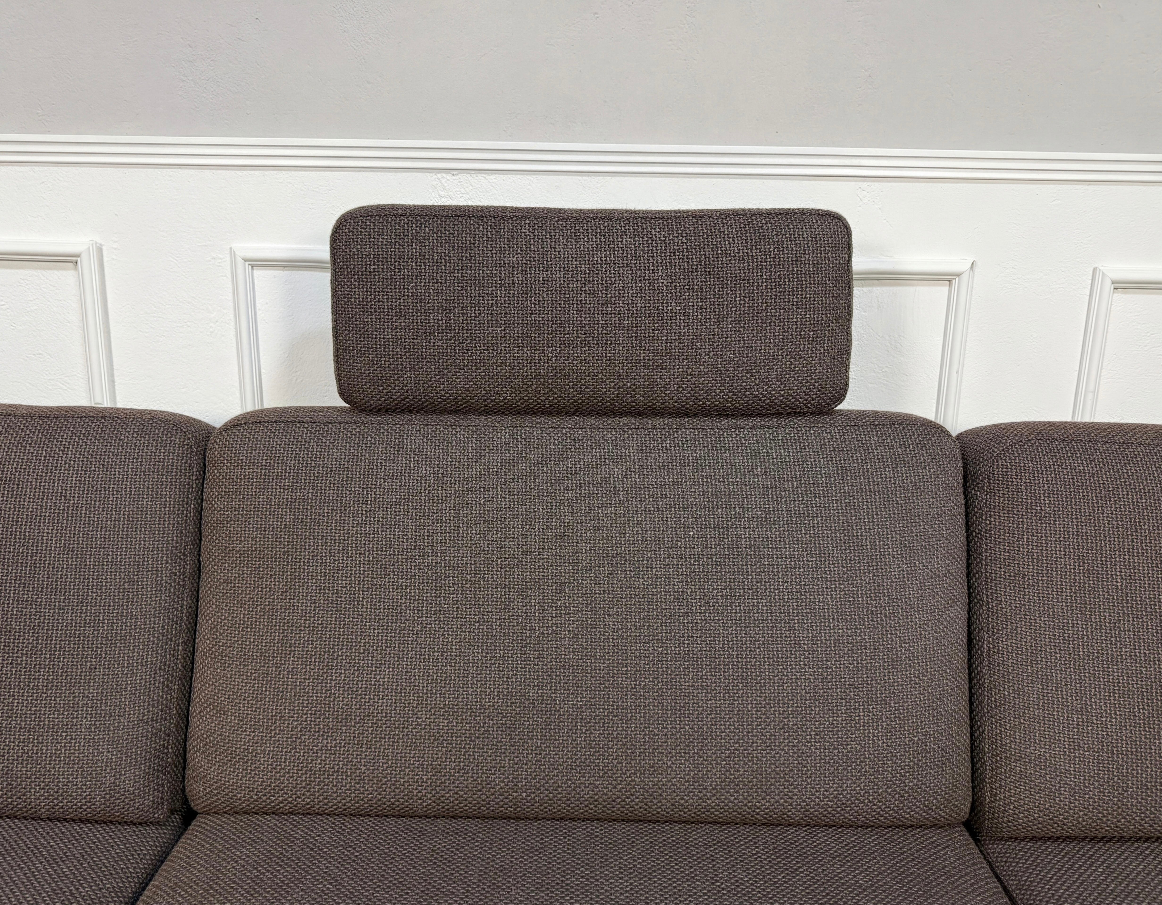 Gebrauchtes braunes Brühl Ecksofa Designer Stoff Sofa vor einer Wand, stilvoll und modern eingerichtet.