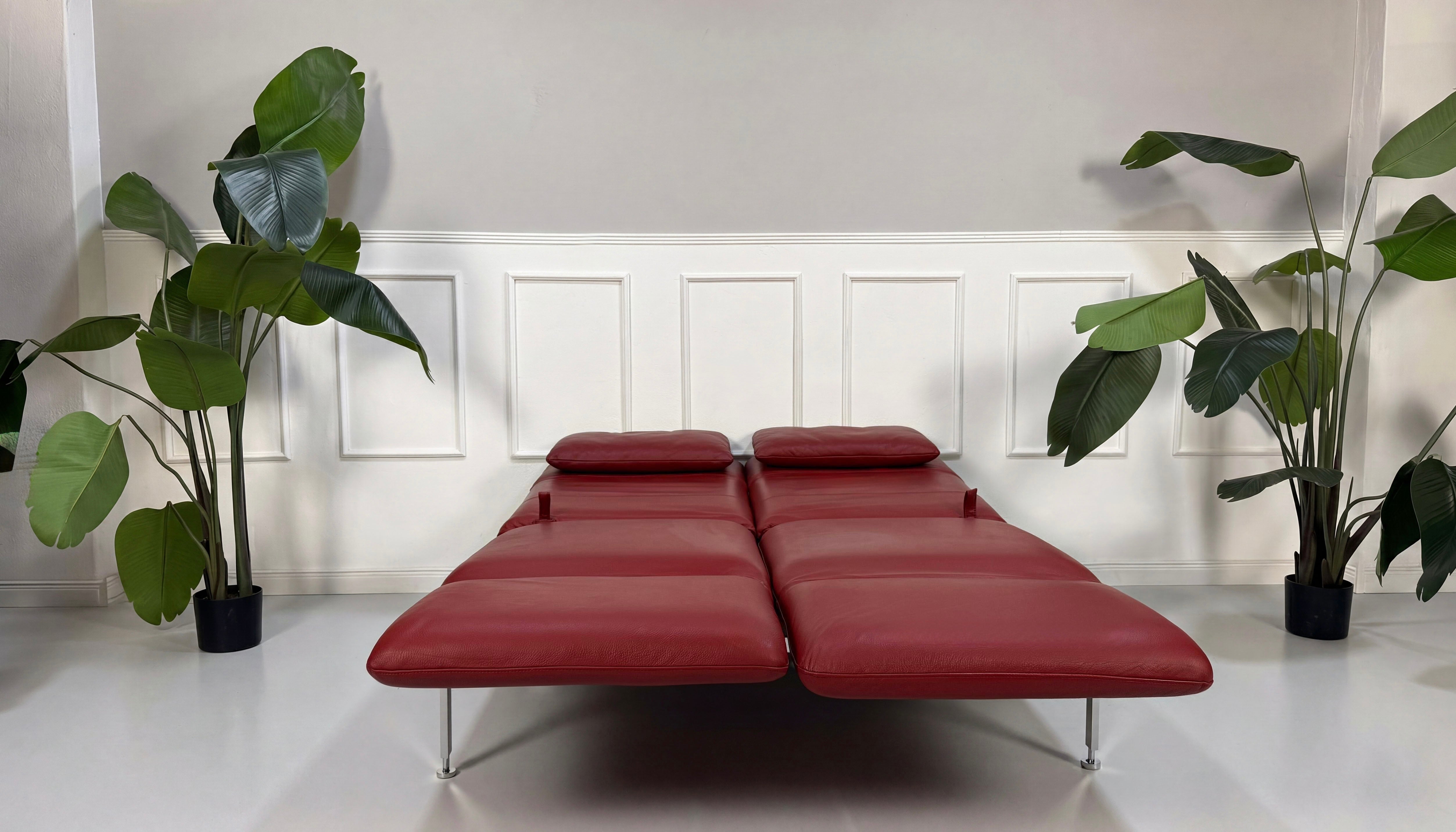 Gebrauchtes rotes Brühl Roro Designer Leder Sofa vor einer Wand, stilvoll und modern eingerichtet.