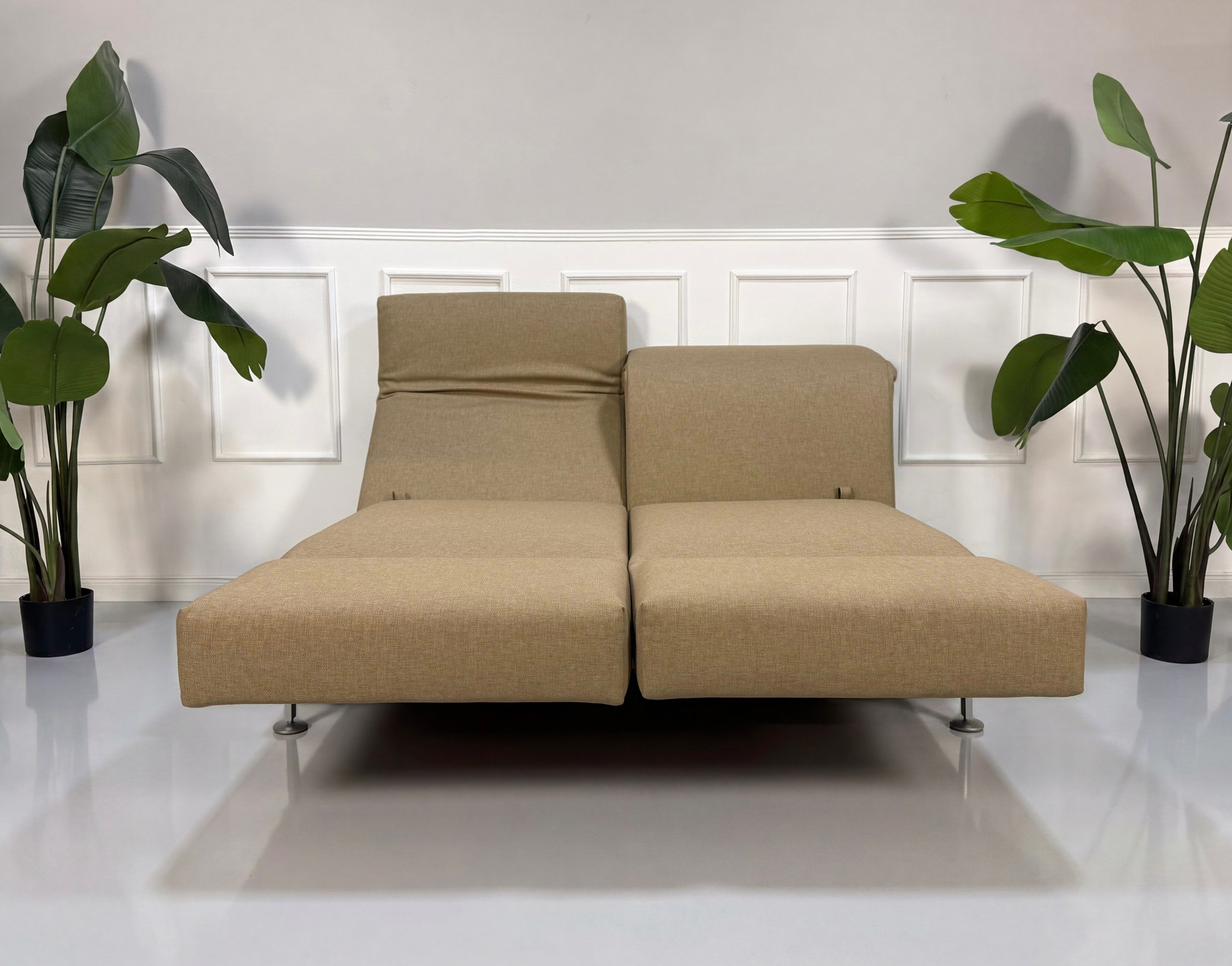 Gebrauchtes beiges Brühl Moule Designer Stoff Sofa vor einer Wand, stilvoll und modern eingerichtet.