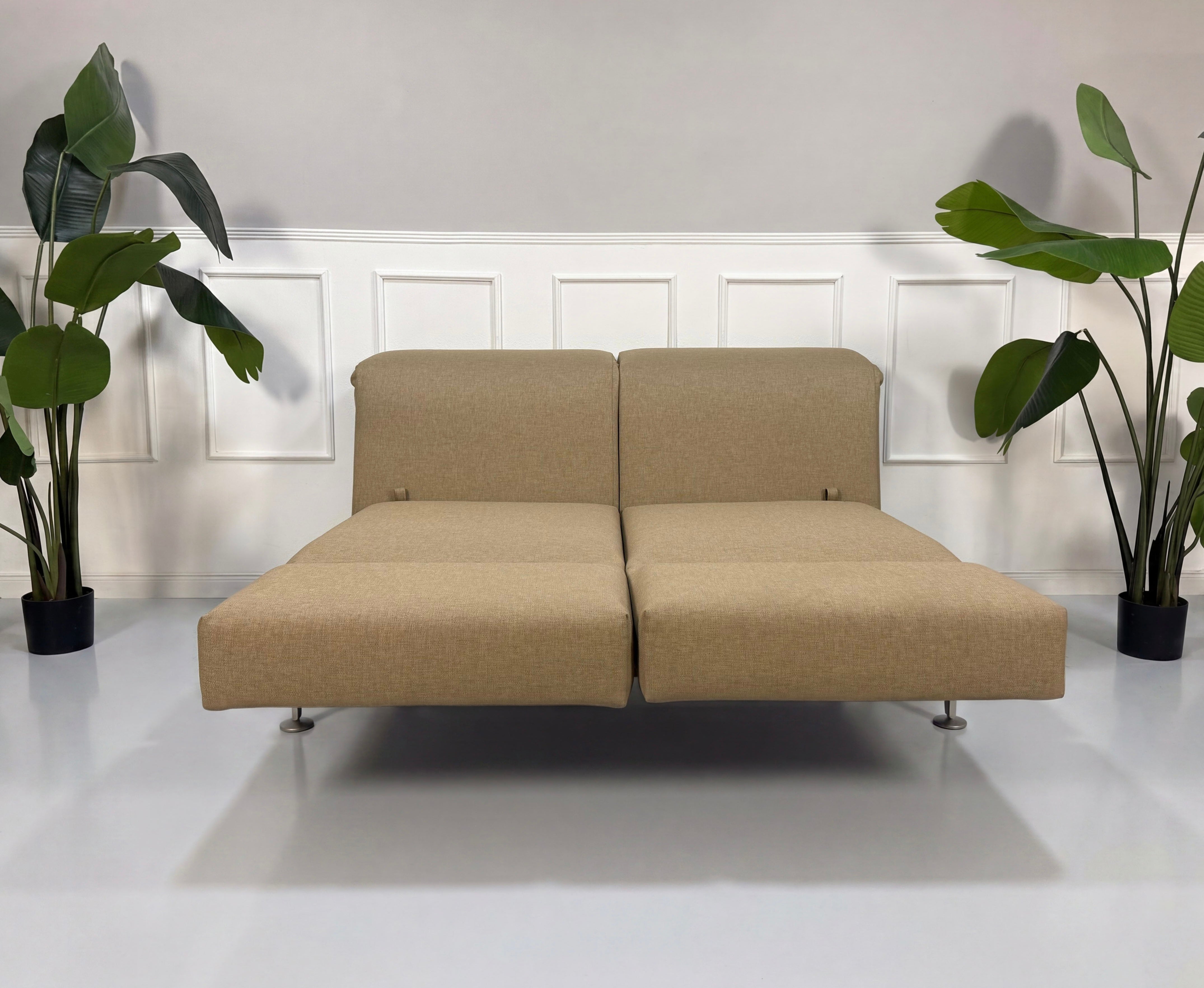 Gebrauchtes beiges Brühl Moule Designer Stoff Sofa vor einer Wand, stilvoll und modern eingerichtet.