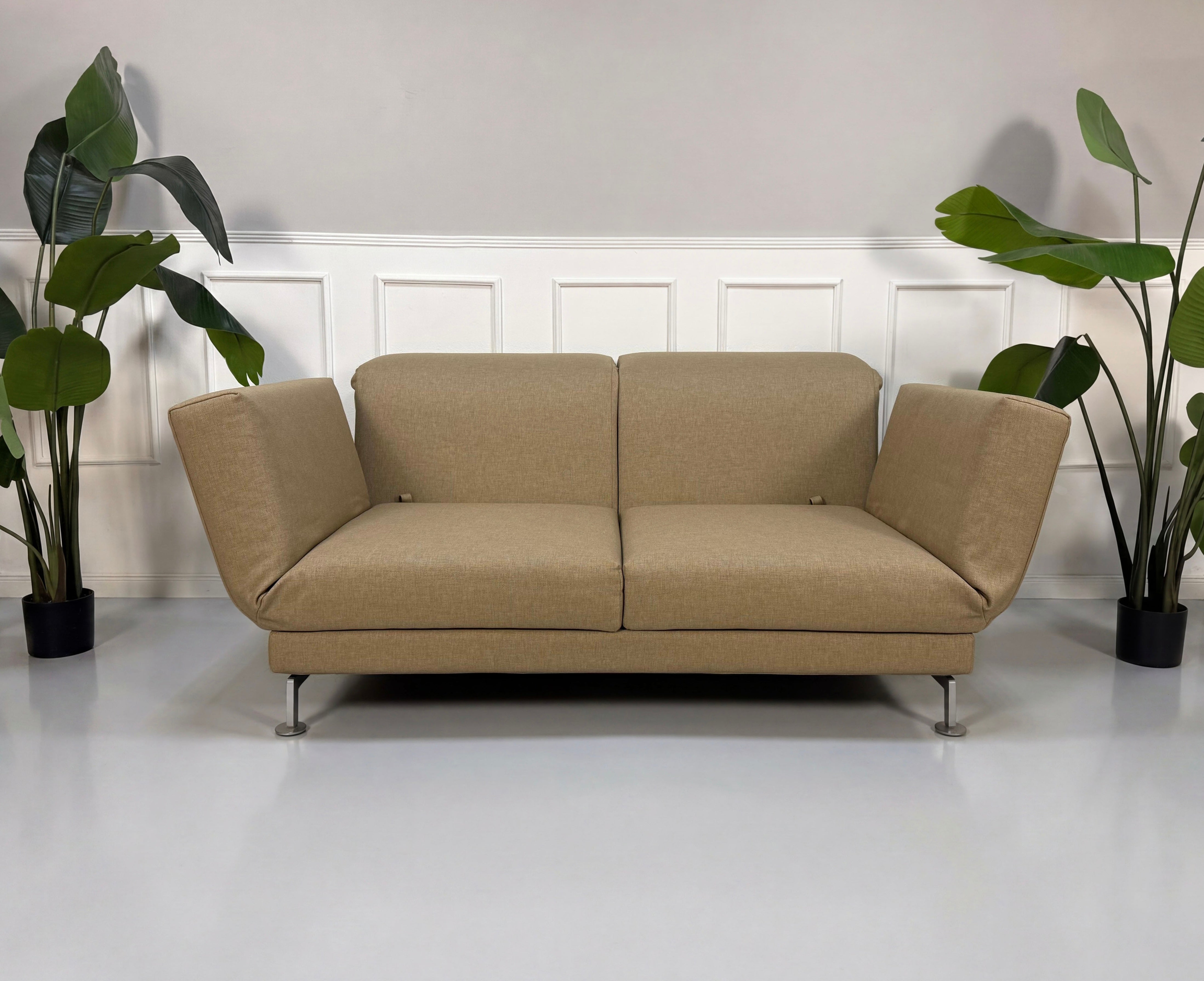 Gebrauchtes beiges Brühl Moule Designer Stoff Sofa vor einer Wand, stilvoll und modern eingerichtet.
