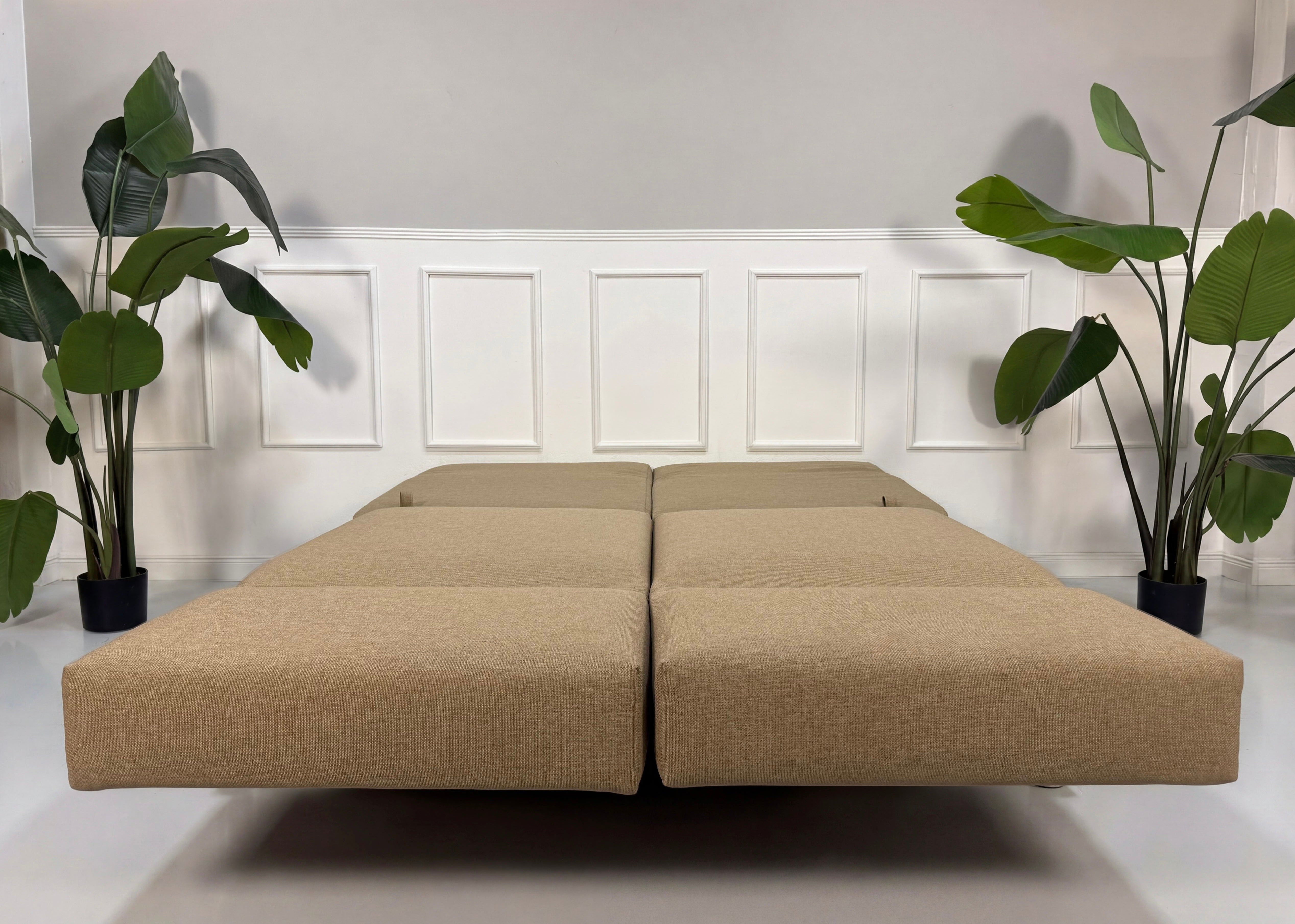 Gebrauchtes beiges Brühl Moule Designer Stoff Sofa vor einer Wand, stilvoll und modern eingerichtet.