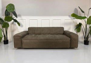 Gebrauchtes braunes Rolf Benz Mio Designer Leder Sofa vor einer Wand, stilvoll und modern eingerichtet.
