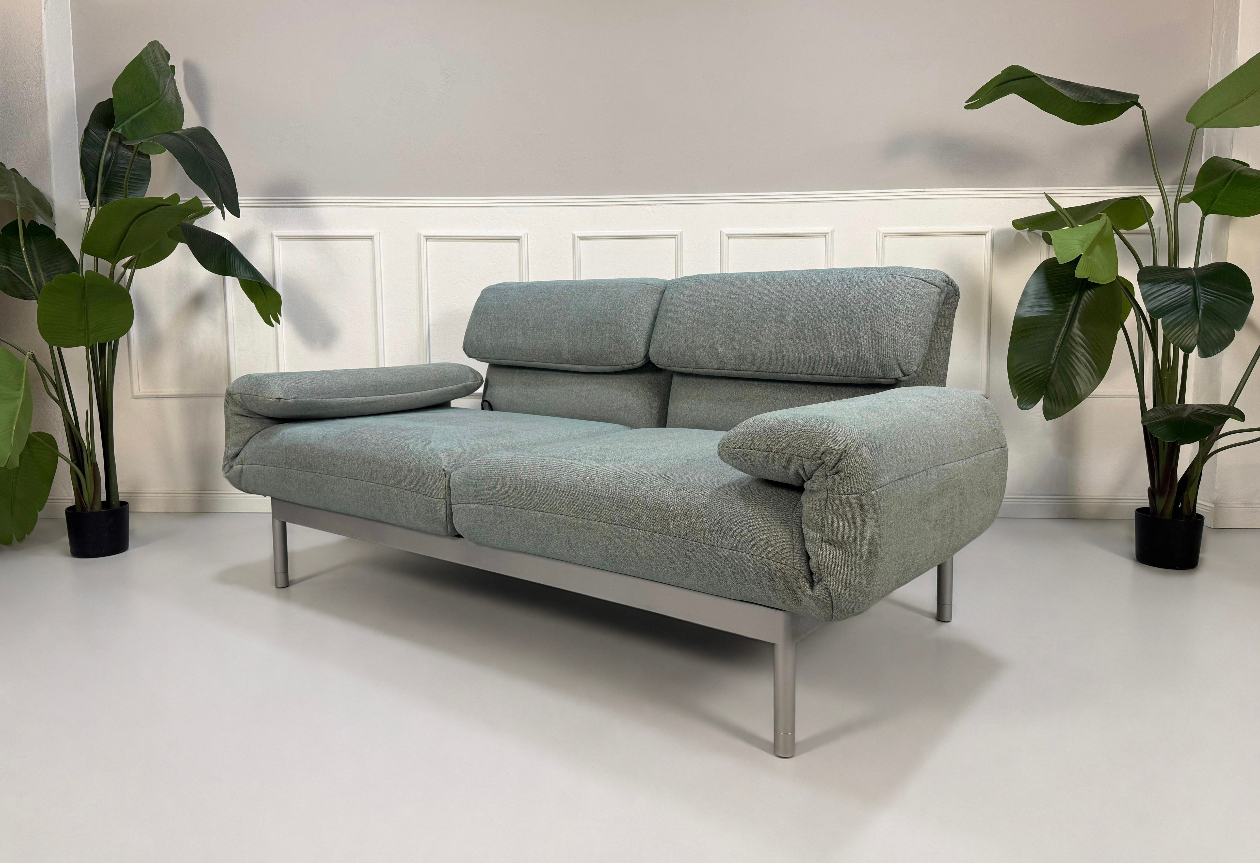 Gebrauchtes graues mint Rolf Benz Plura Designer Stoff Sofa vor einer Wand, stilvoll und modern eingerichtet.