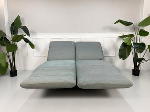 Gebrauchtes graues mint Rolf Benz Plura Designer Stoff Sofa vor einer Wand, stilvoll und modern eingerichtet.
