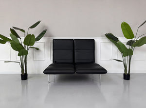 Gebrauchtes schwarzes Brühl Roro Small Designer Leder Sofa vor einer Wand, stilvoll und modern eingerichtet.