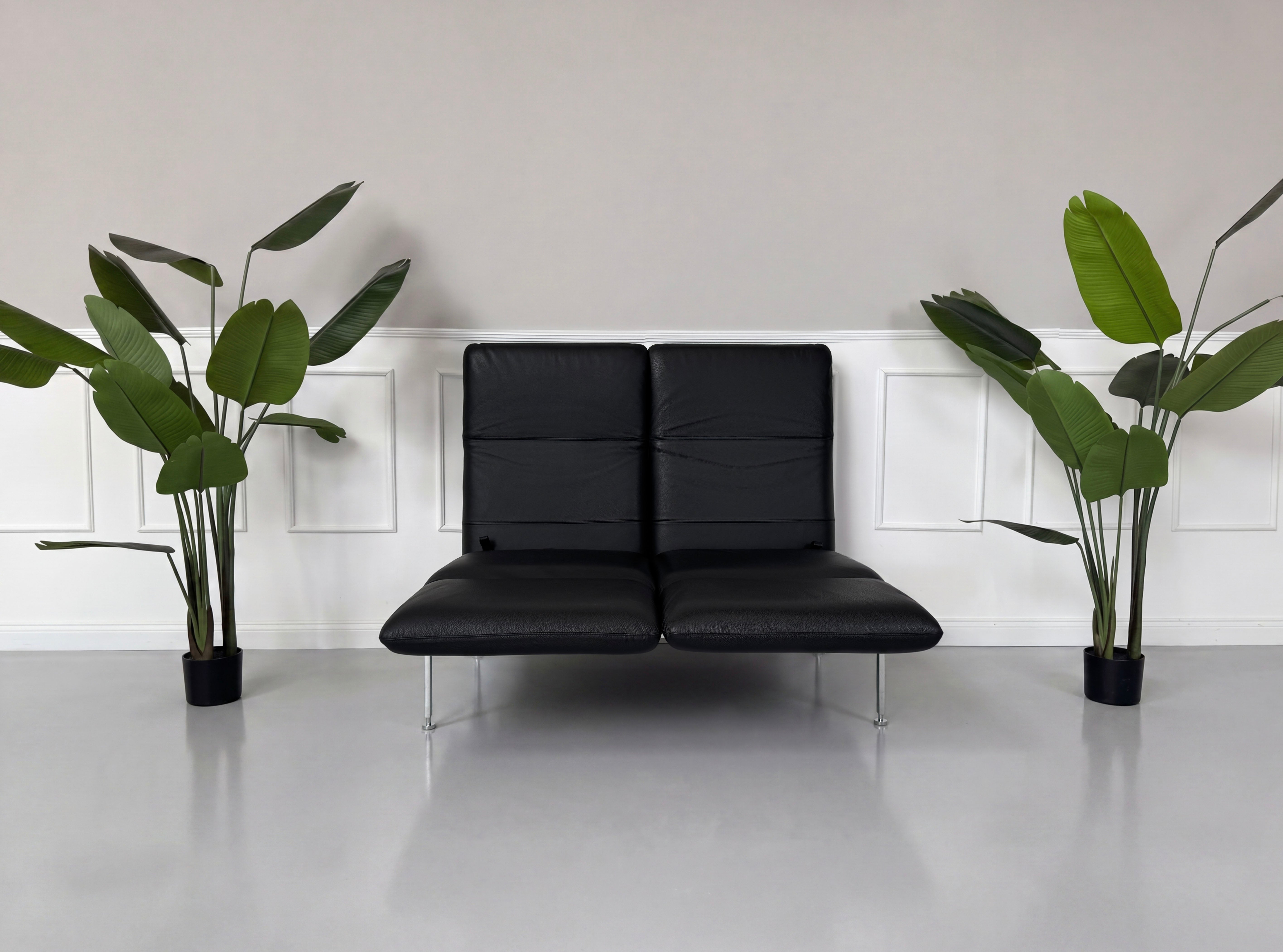 Gebrauchtes schwarzes Brühl Roro Small Designer Leder Sofa vor einer Wand, stilvoll und modern eingerichtet.