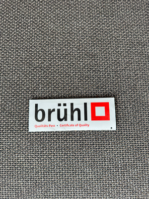 Gebrauchtes braun graues Brühl Moule Designer Stoff Sofa vor einer Wand, stilvoll und modern eingerichtet.