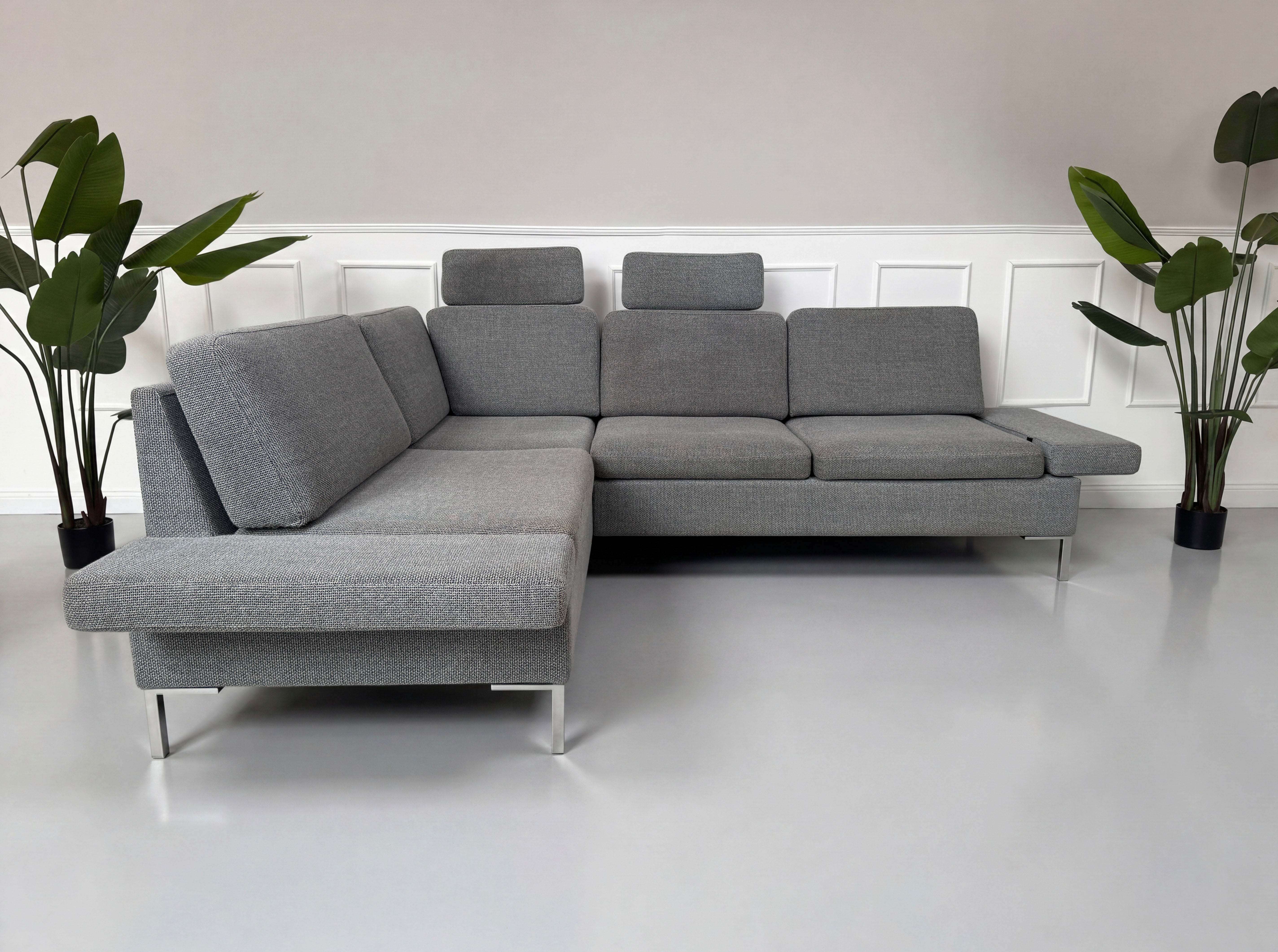 Gebrauchtes graues Brühl Alba Designer Stoff Sofa vor einer Wand, stilvoll und modern eingerichtet.