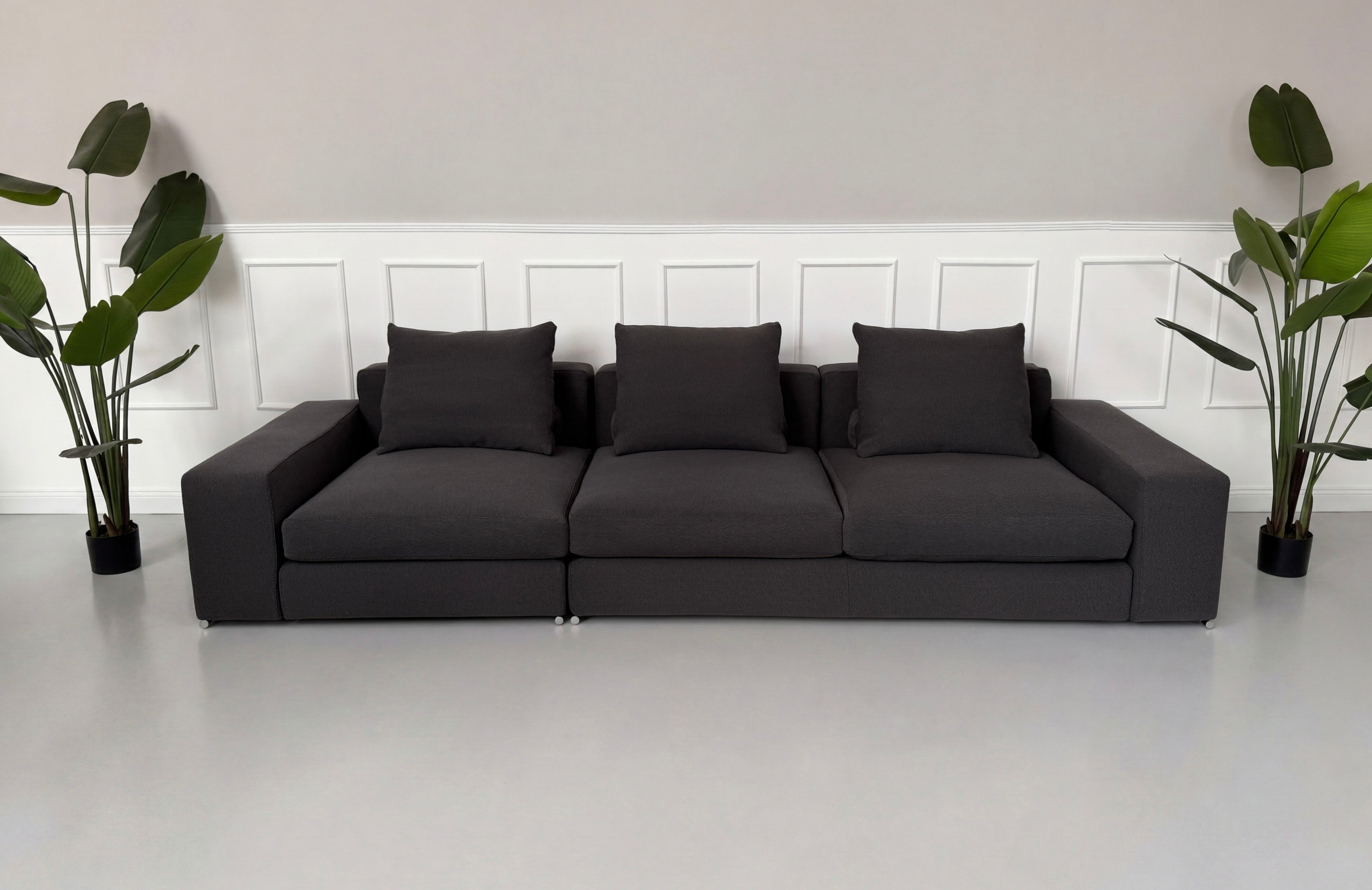 Gebrauchtes graues Minotti Jagger Designer Stoff Sofa vor einer Wand, stilvoll und modern eingerichtet.
