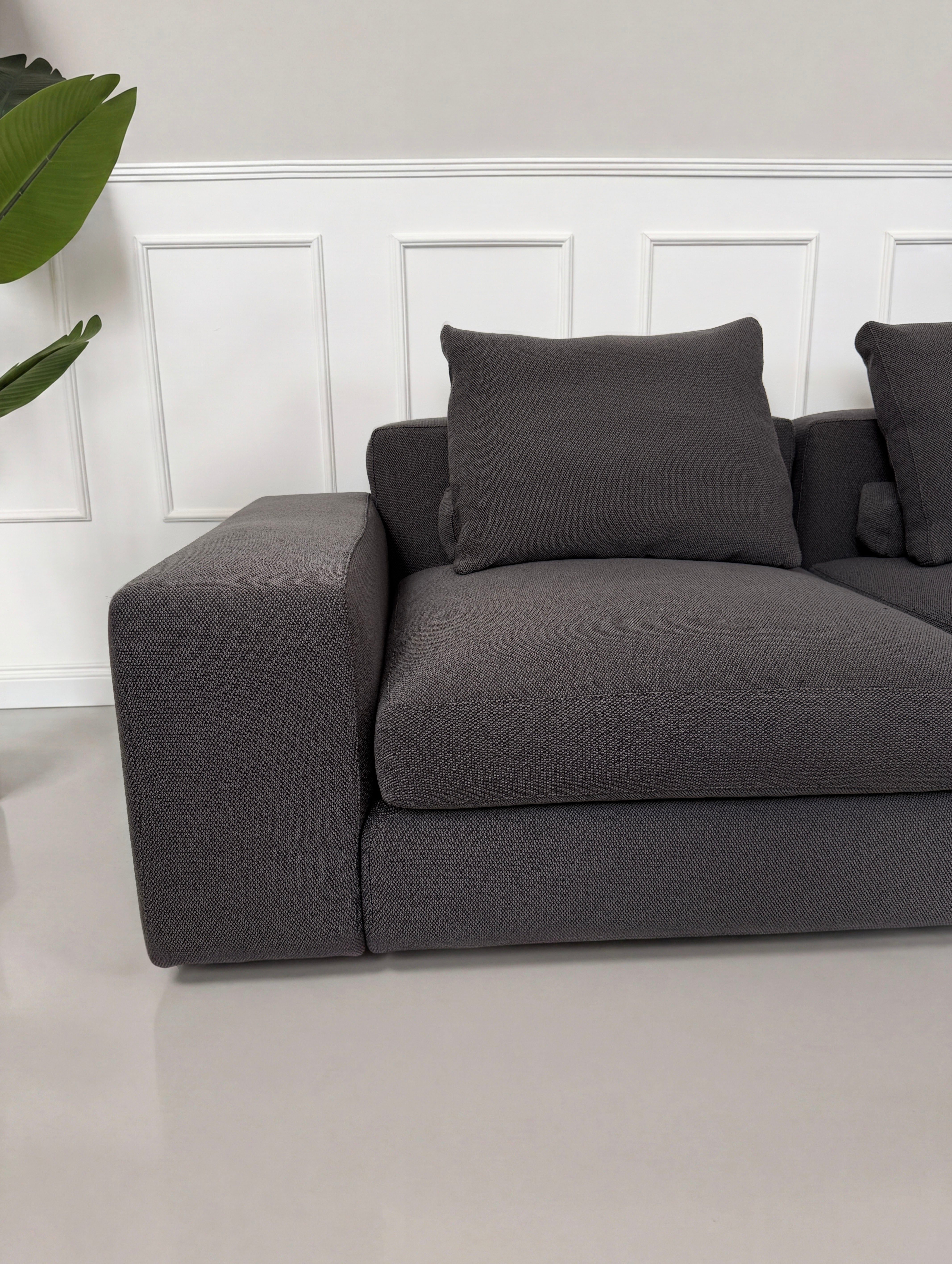 Gebrauchtes graues Minotti Jagger Designer Stoff Sofa vor einer Wand, stilvoll und modern eingerichtet.