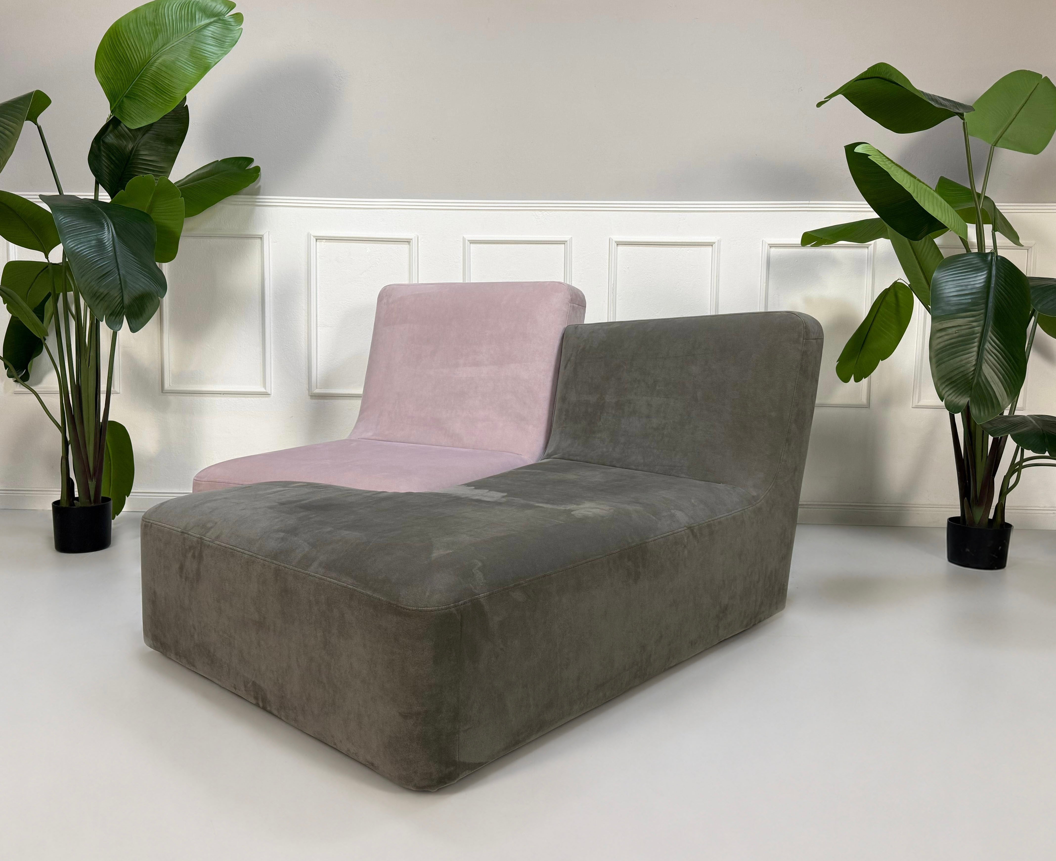 Gebrauchtes grau pinkes Ligne Roset Confluences Designer Stoff Sofa vor einer Wand, stilvoll und modern eingerichtet.
