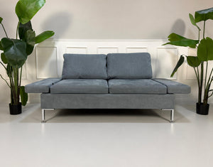 Gebrauchtes blaues Brühl Alba Designer Stoff Sofa vor einer Wand, stilvoll und modern eingerichtet.