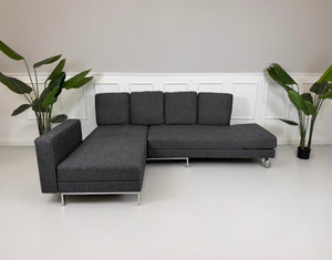 Gebrauchtes graues Brühl Four Two Designer Stoff Sofa vor einer Wand, stilvoll und modern eingerichtet.