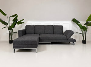 Gebrauchtes graues Brühl Four Two Designer Stoff Sofa vor einer Wand, stilvoll und modern eingerichtet.