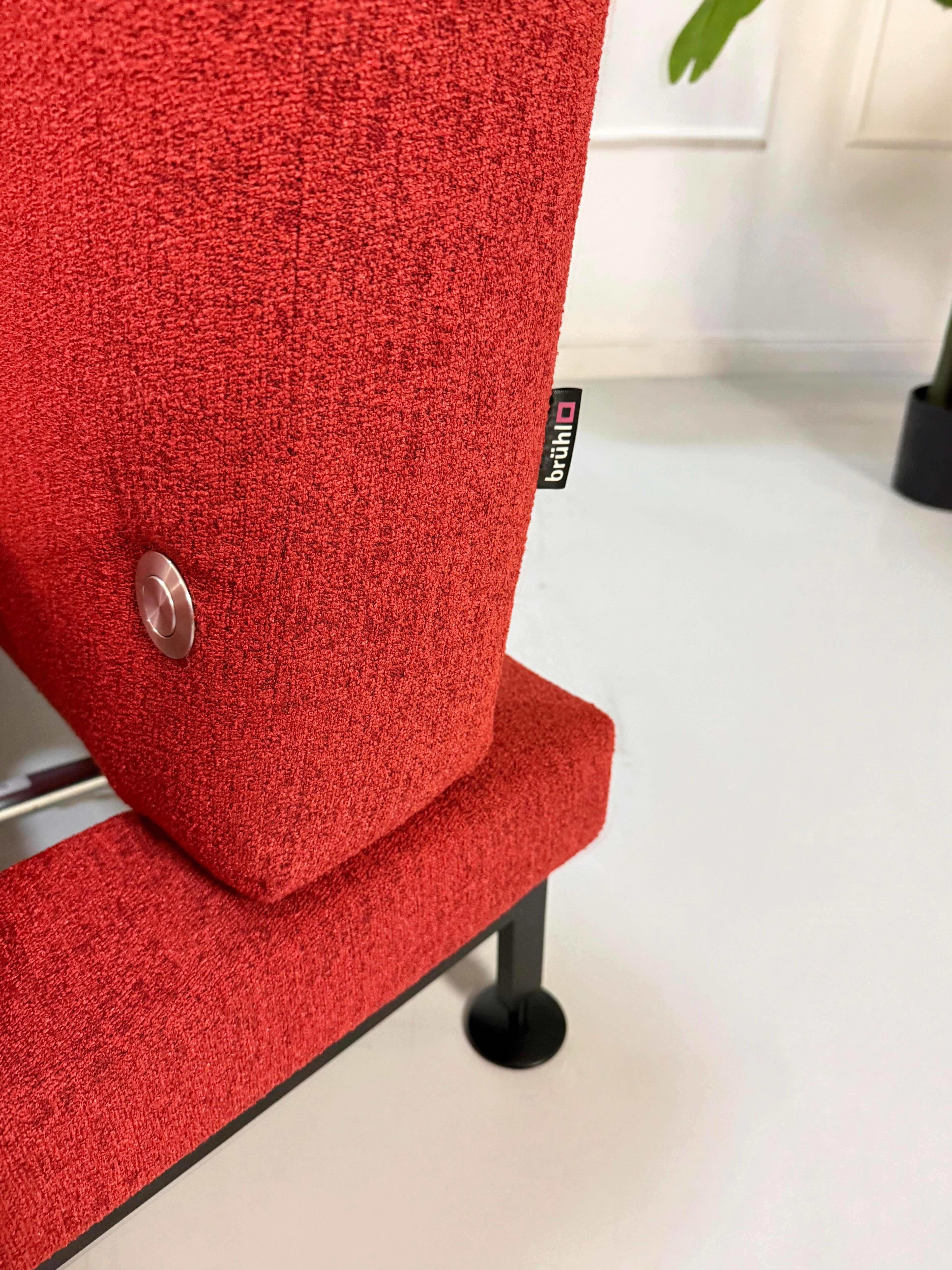 Gebrauchtes rotes Brühl Moule Small Designer Stoff Sofa vor einer Wand, stilvoll und modern eingerichtet.