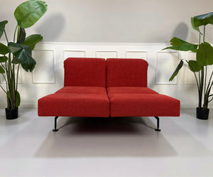 Gebrauchtes rotes Brühl Moule Small Designer Stoff Sofa vor einer Wand, stilvoll und modern eingerichtet.
