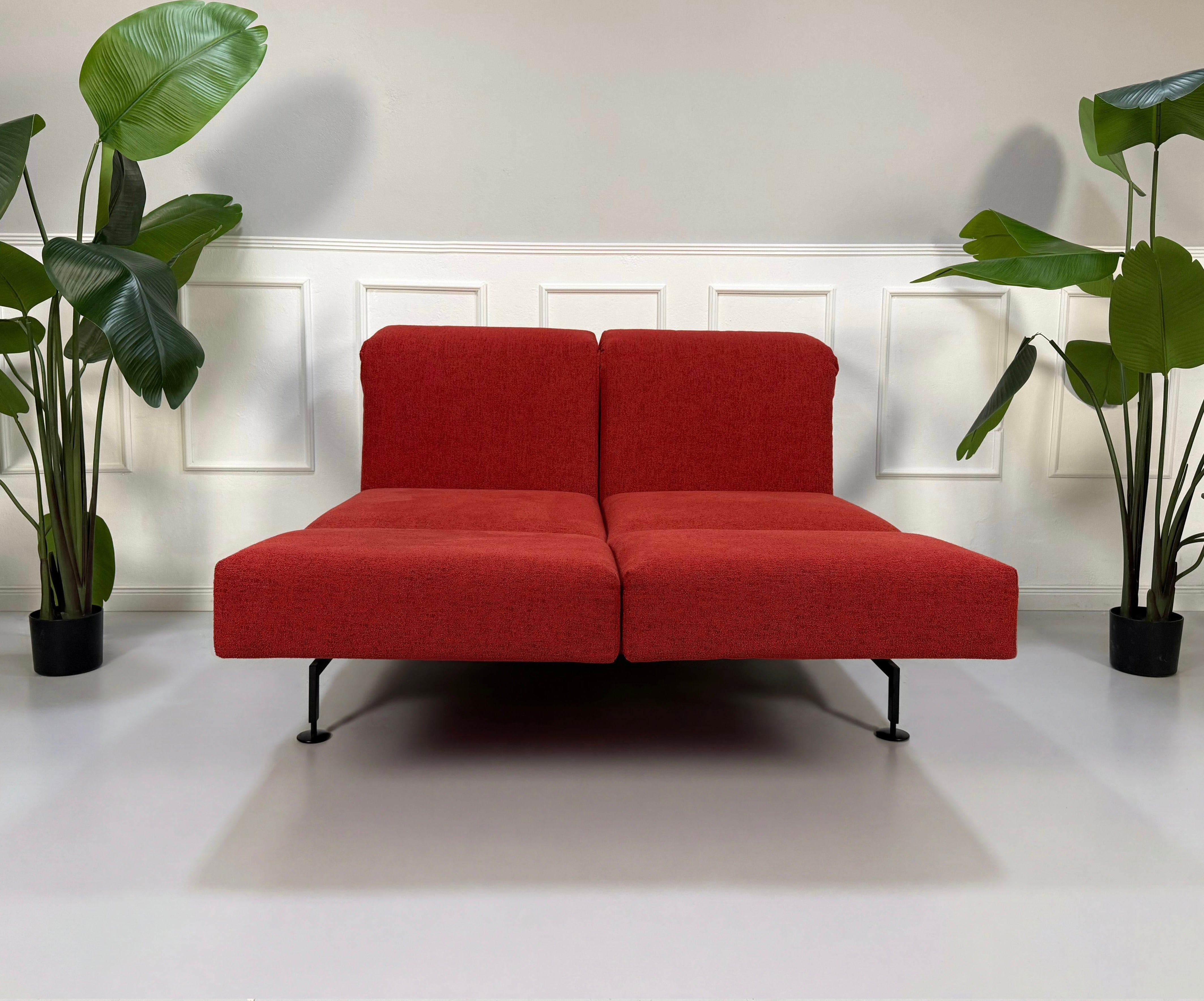 Gebrauchtes rotes Brühl Moule Small Designer Stoff Sofa vor einer Wand, stilvoll und modern eingerichtet.