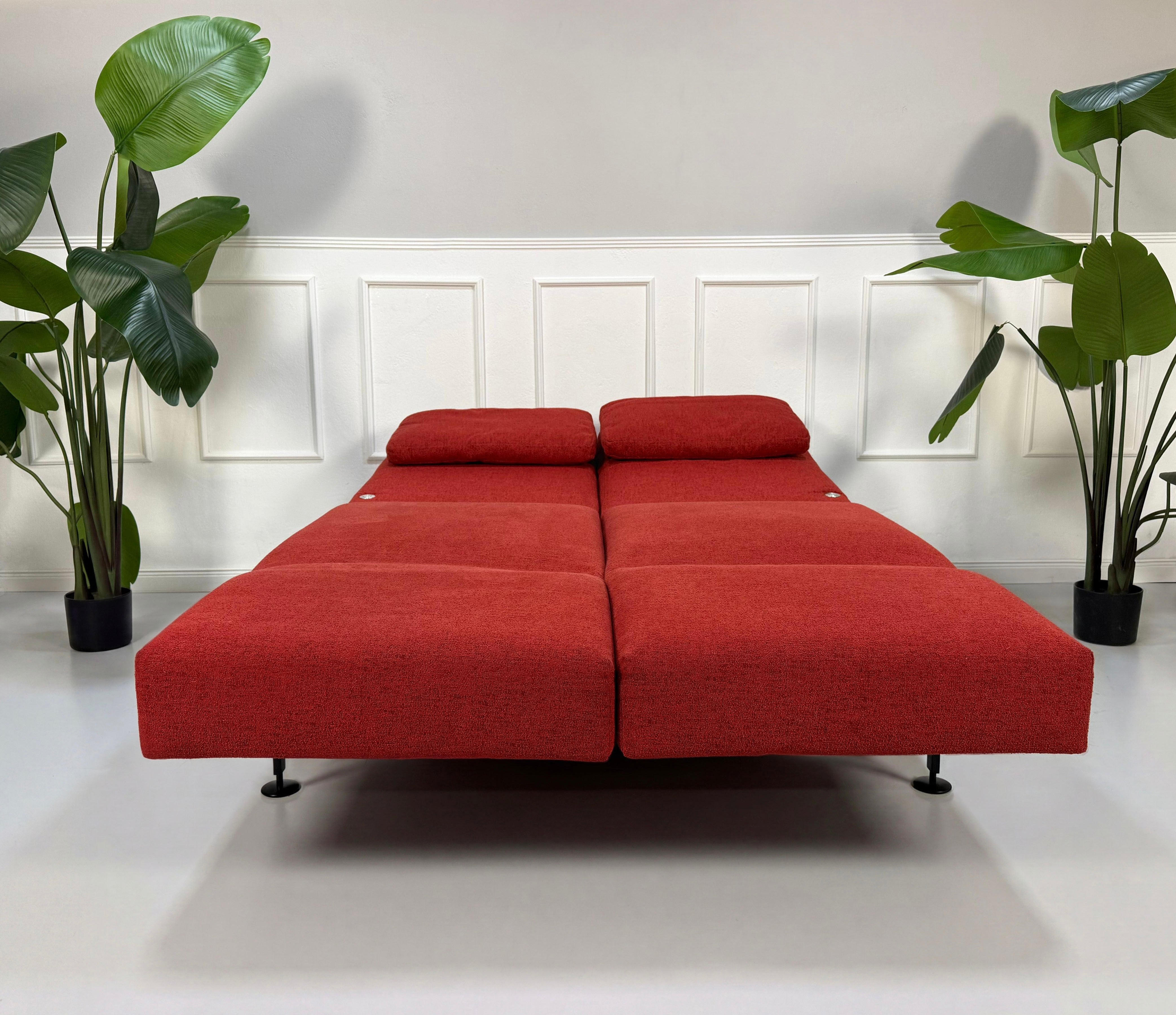 Gebrauchtes rotes Brühl Moule Small Designer Stoff Sofa vor einer Wand, stilvoll und modern eingerichtet.
