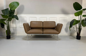 Gebrauchtes braunes Brühl Roro Small Designer Leder Sofa vor einer Wand, stilvoll und modern eingerichtet.