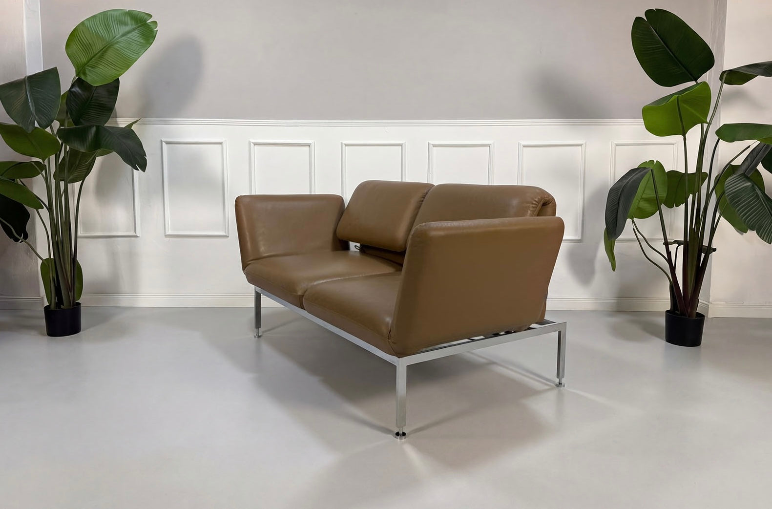 Gebrauchtes braunes Brühl Roro Small Designer Leder Sofa vor einer Wand, stilvoll und modern eingerichtet.