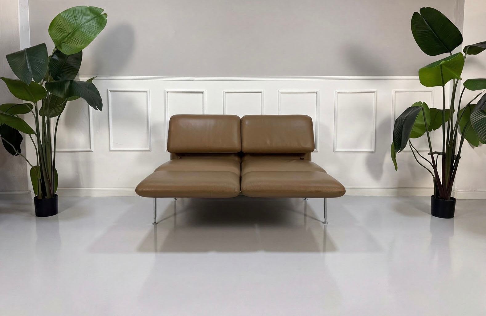 Gebrauchtes braunes Brühl Roro Small Designer Leder Sofa vor einer Wand, stilvoll und modern eingerichtet.