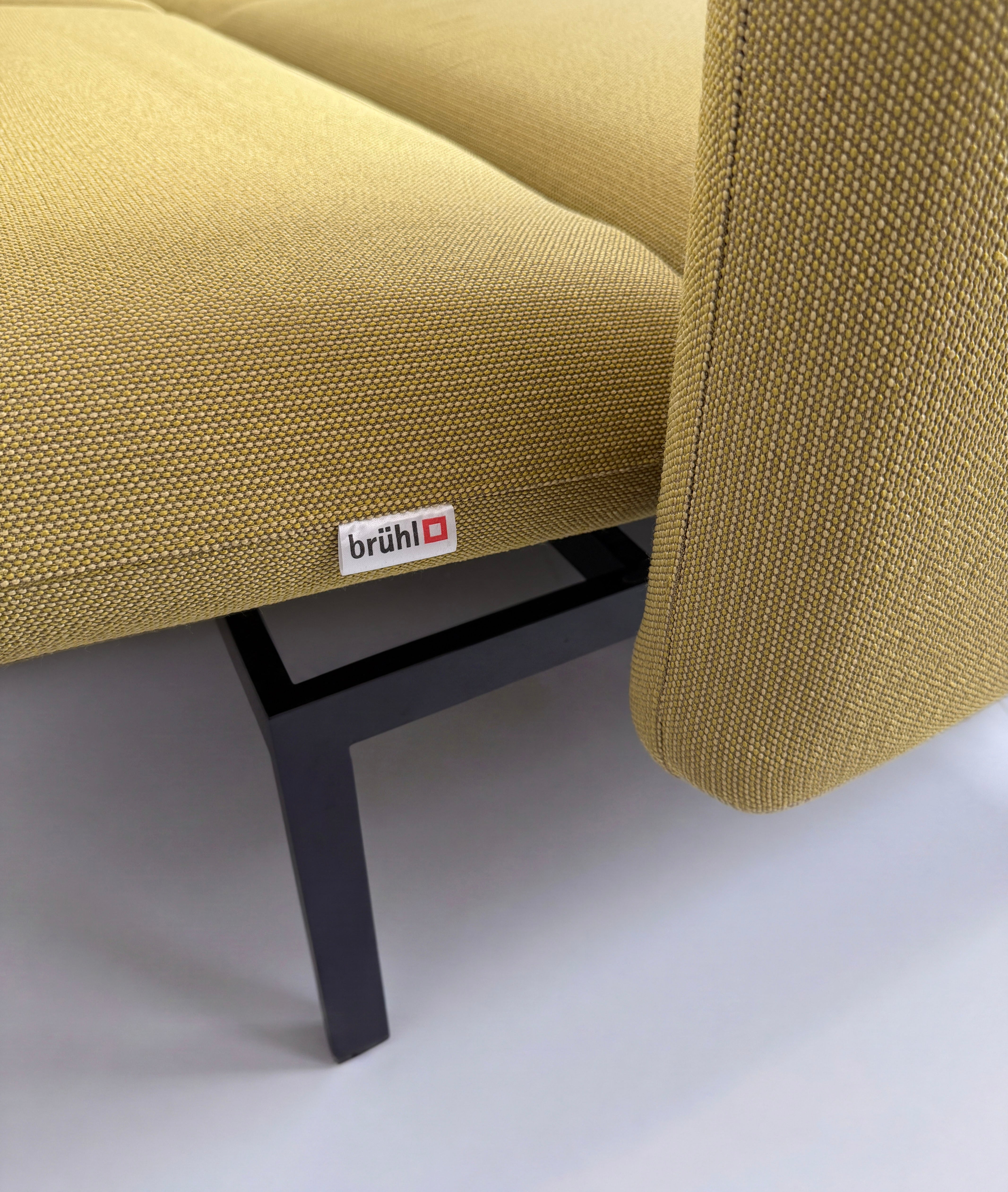 Gebrauchtes gelbes Brühl Roro Designer Stoff Sofa vor einer Wand, stilvoll und modern eingerichtet.
