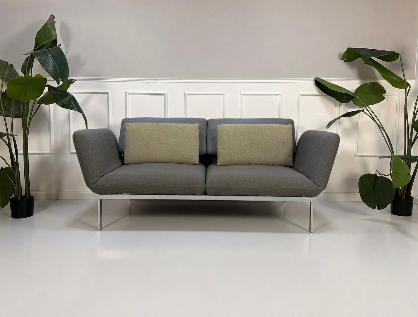 Gebrauchtes graues Brühl Roro Designer Stoff Sofa vor einer Wand, stilvoll und modern eingerichtet.

