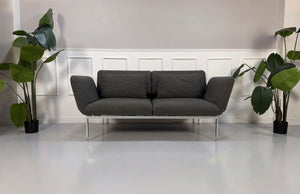 Gebrauchtes graues Brühl Roro Designer Stoff Sofa vor einer Wand, stilvoll und modern eingerichtet.
