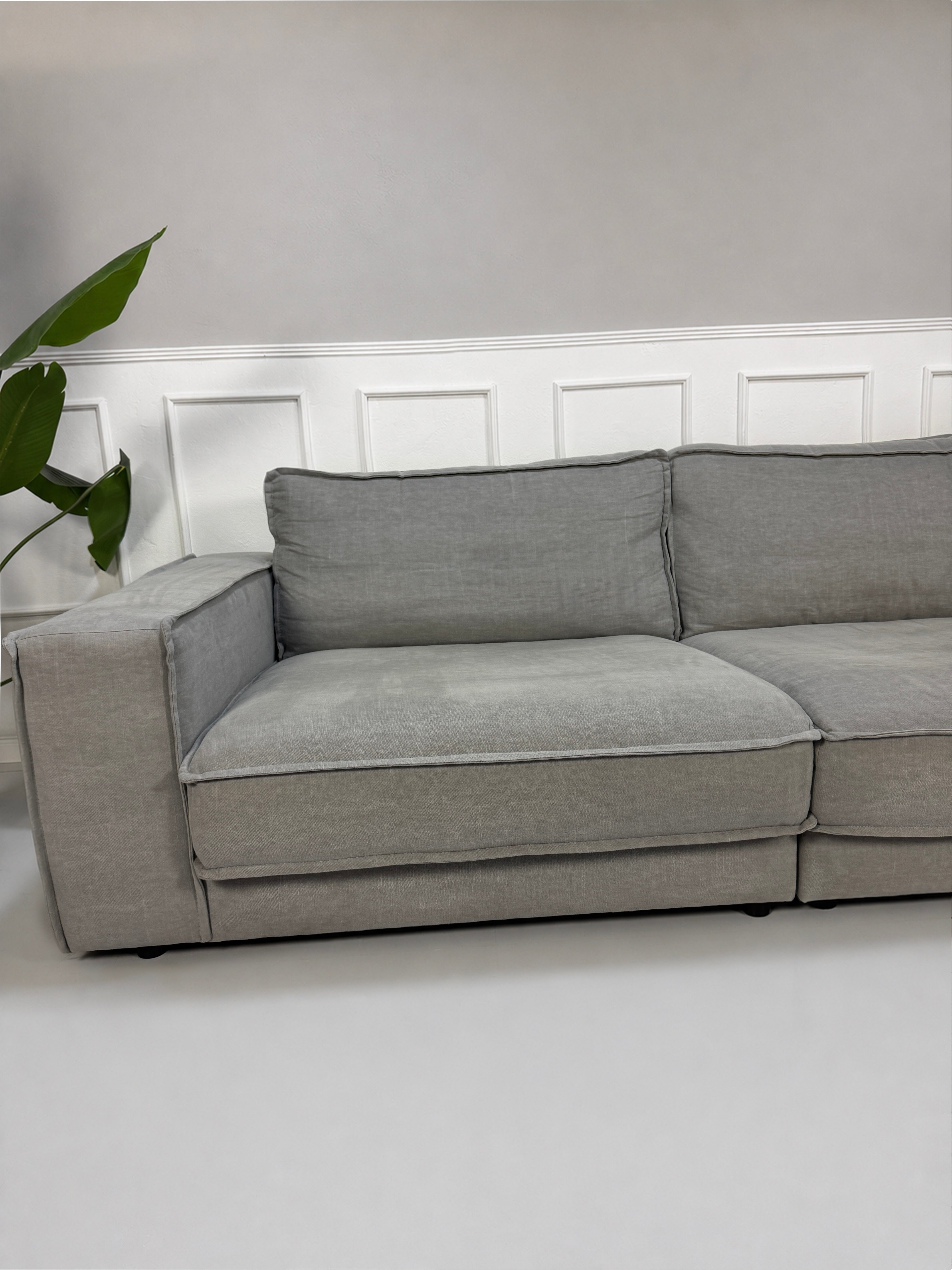 Gebrauchtes graues Bolia Noora Designer Stoff Sofa vor einer Wand, stilvoll und modern eingerichtet.