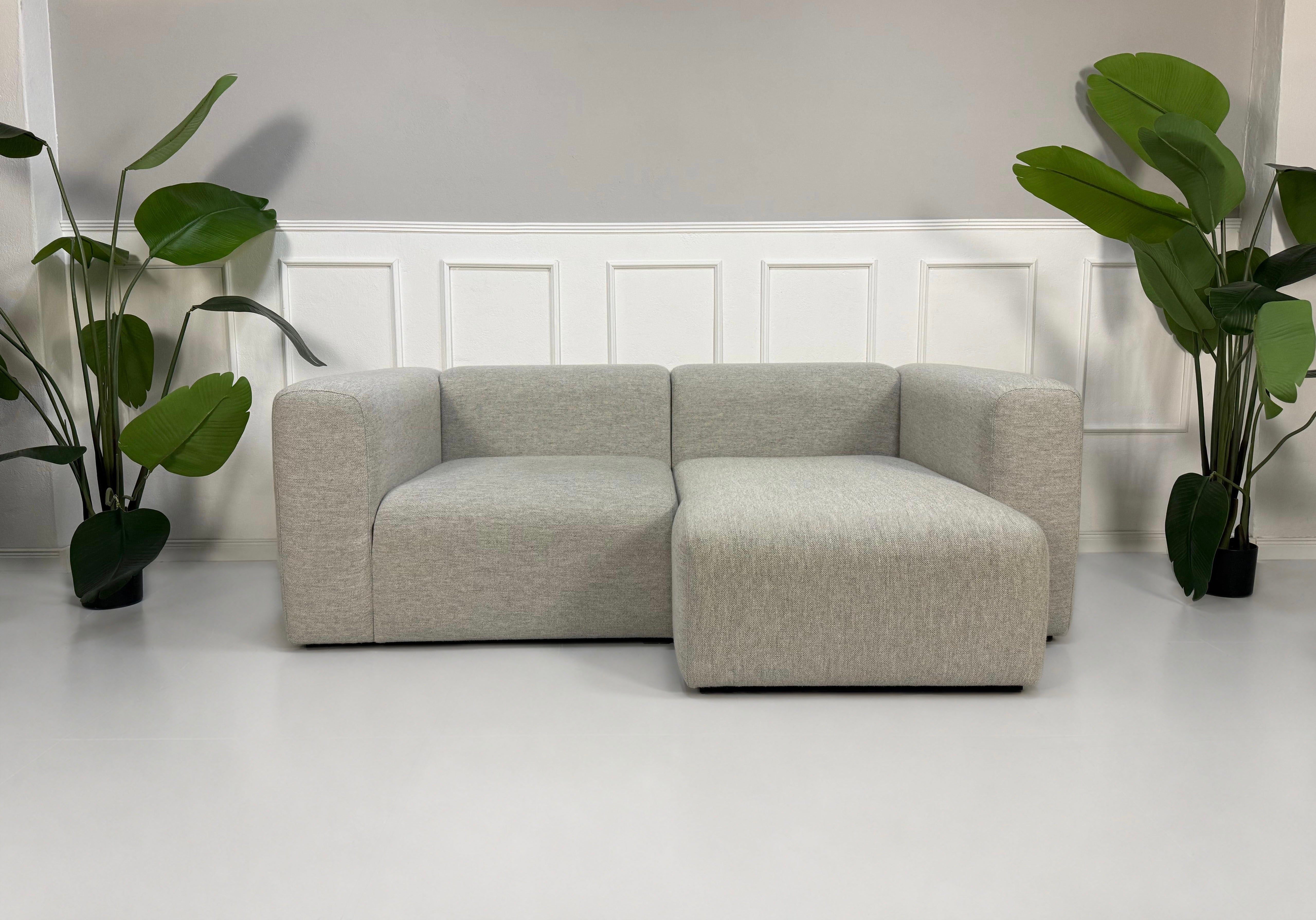 Gebrauchtes graues Hay Mags Designer Stoff Sofa vor einer Wand, stilvoll und modern eingerichtet.