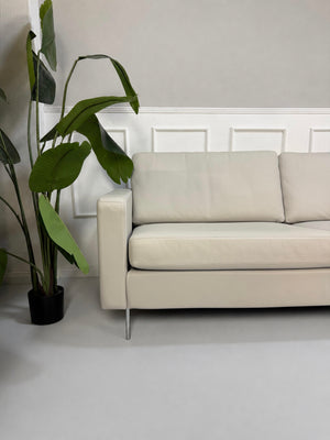Gebrauchtes graues COR Conseta Designer Leder Sofa vor einer Wand, stilvoll und modern eingerichtet.