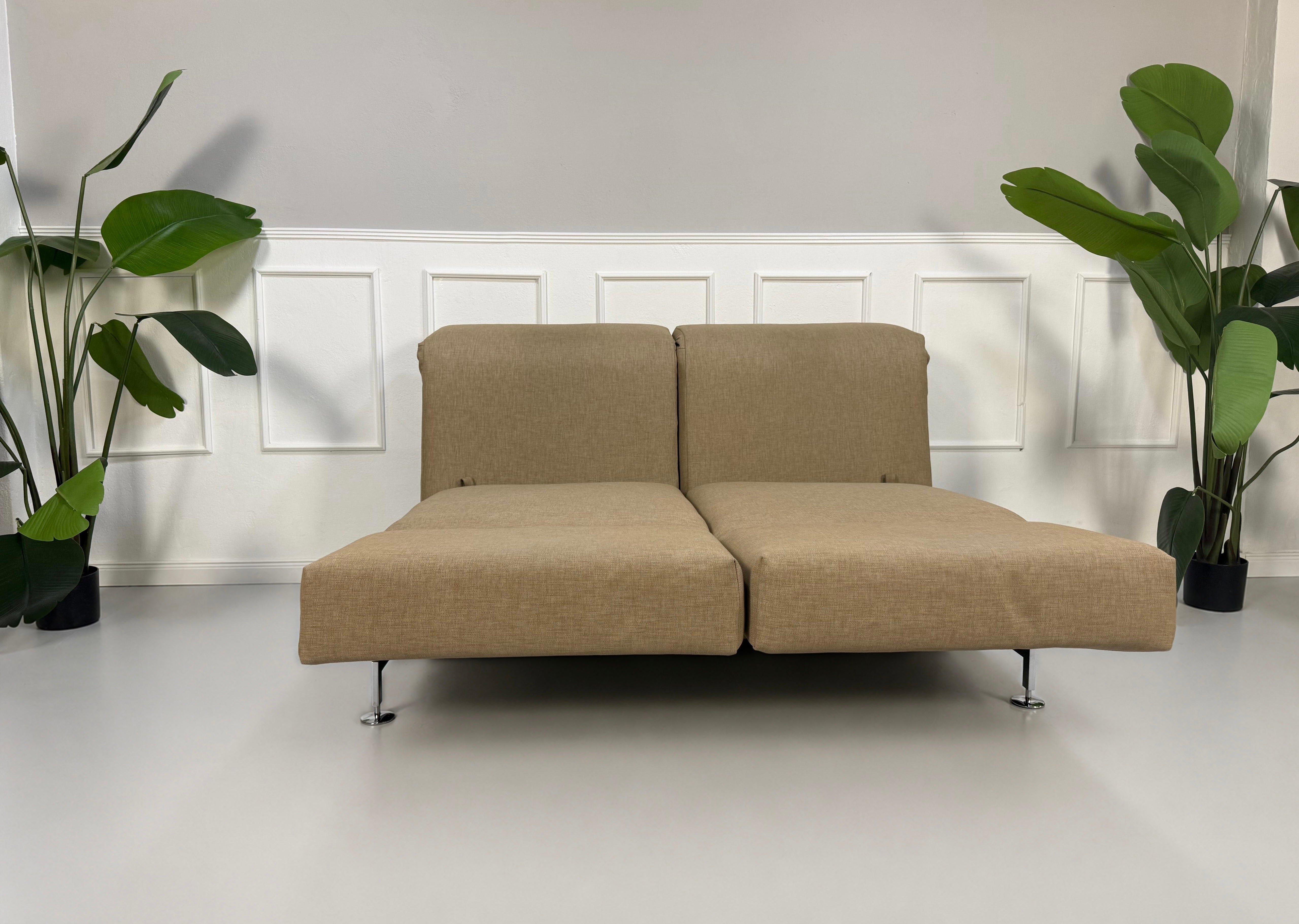 Gebrauchtes beiges Brühl Moule Designer Stoff Sofa vor einer Wand, stilvoll und modern eingerichtet.