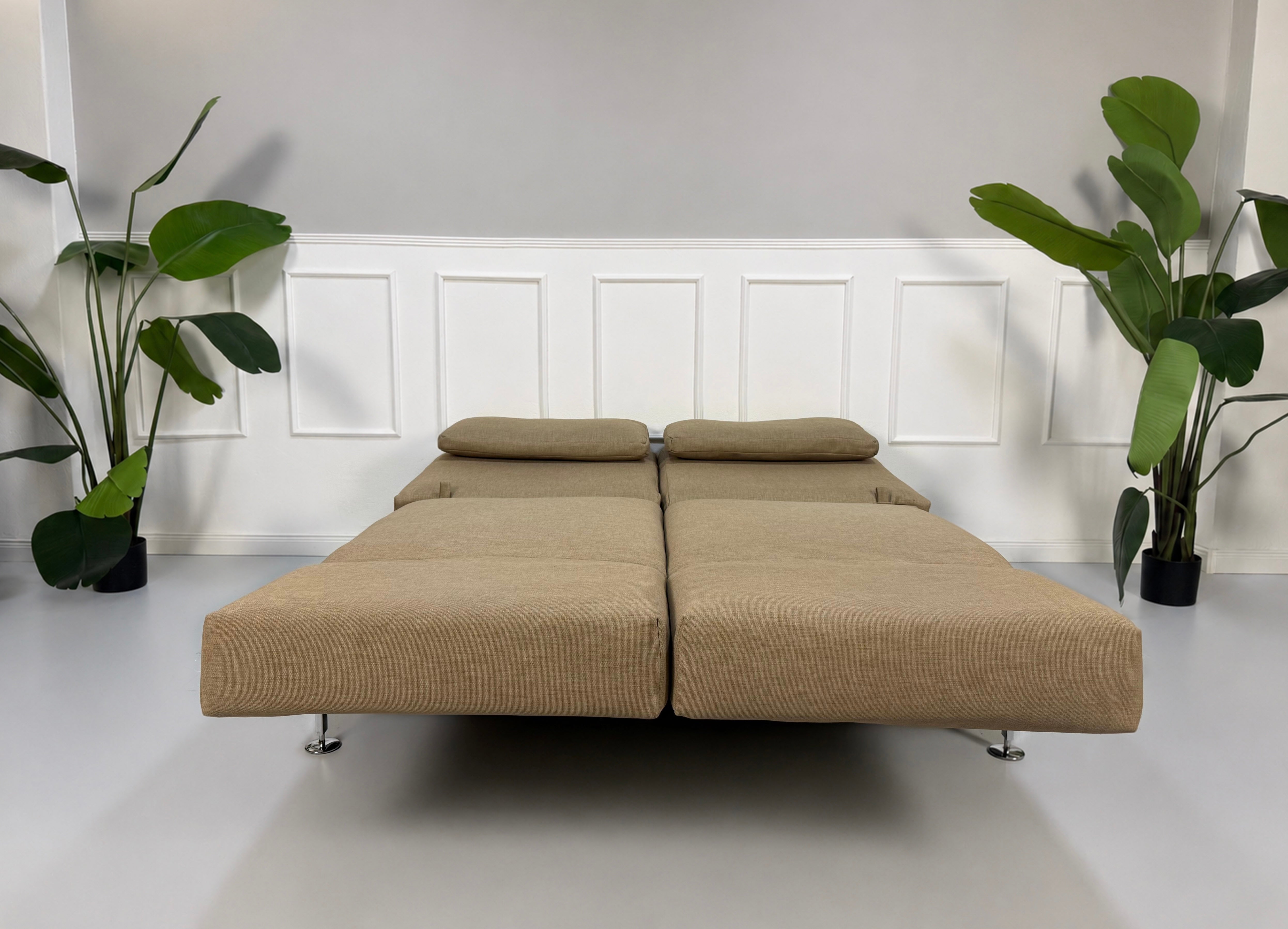 Gebrauchtes beiges Brühl Moule Designer Stoff Sofa vor einer Wand, stilvoll und modern eingerichtet.