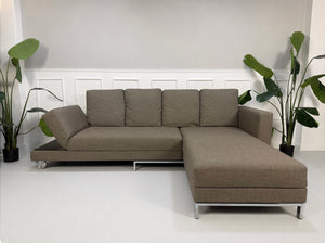 Gebrauchtes braunes Brühl Fourtwo Designer Stoff Sofa vor einer Wand, stilvoll und modern eingerichtet.