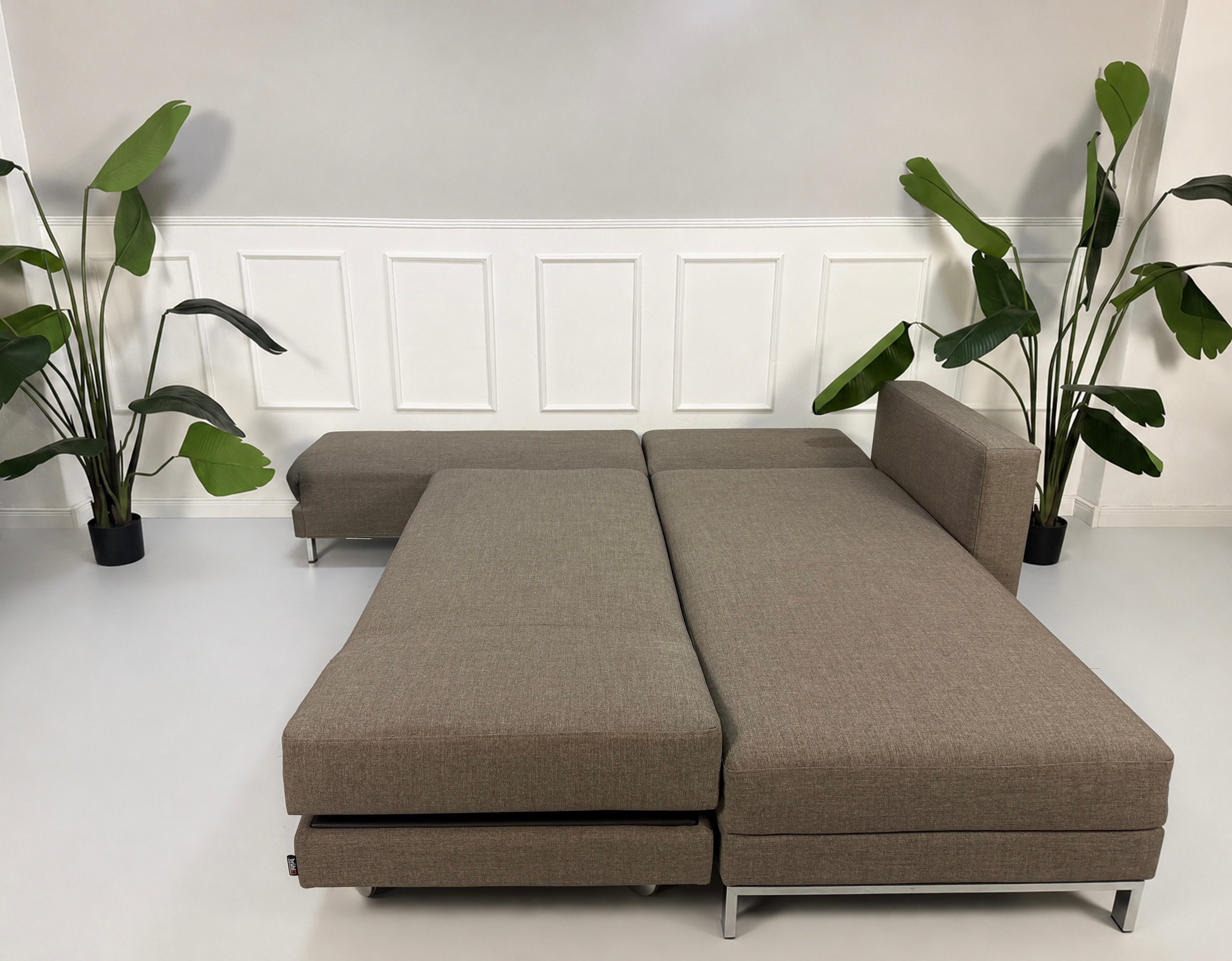 Gebrauchtes braunes Brühl Fourtwo Designer Stoff Sofa vor einer Wand, stilvoll und modern eingerichtet.