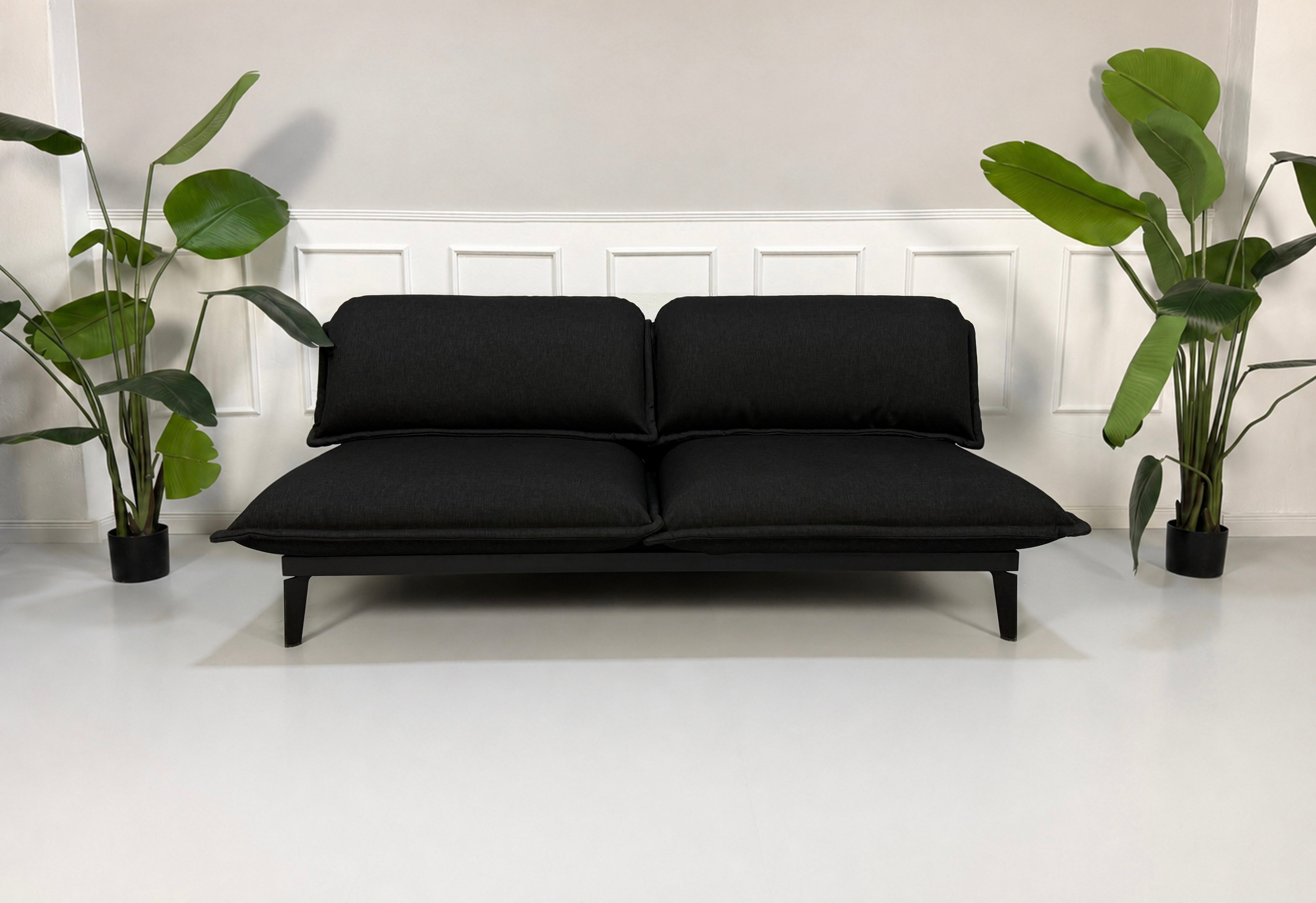 Gebrauchtes schwarzes Rolf Benz Nova Designer Stoff Sofa vor einer Wand, stilvoll und modern eingerichtet.