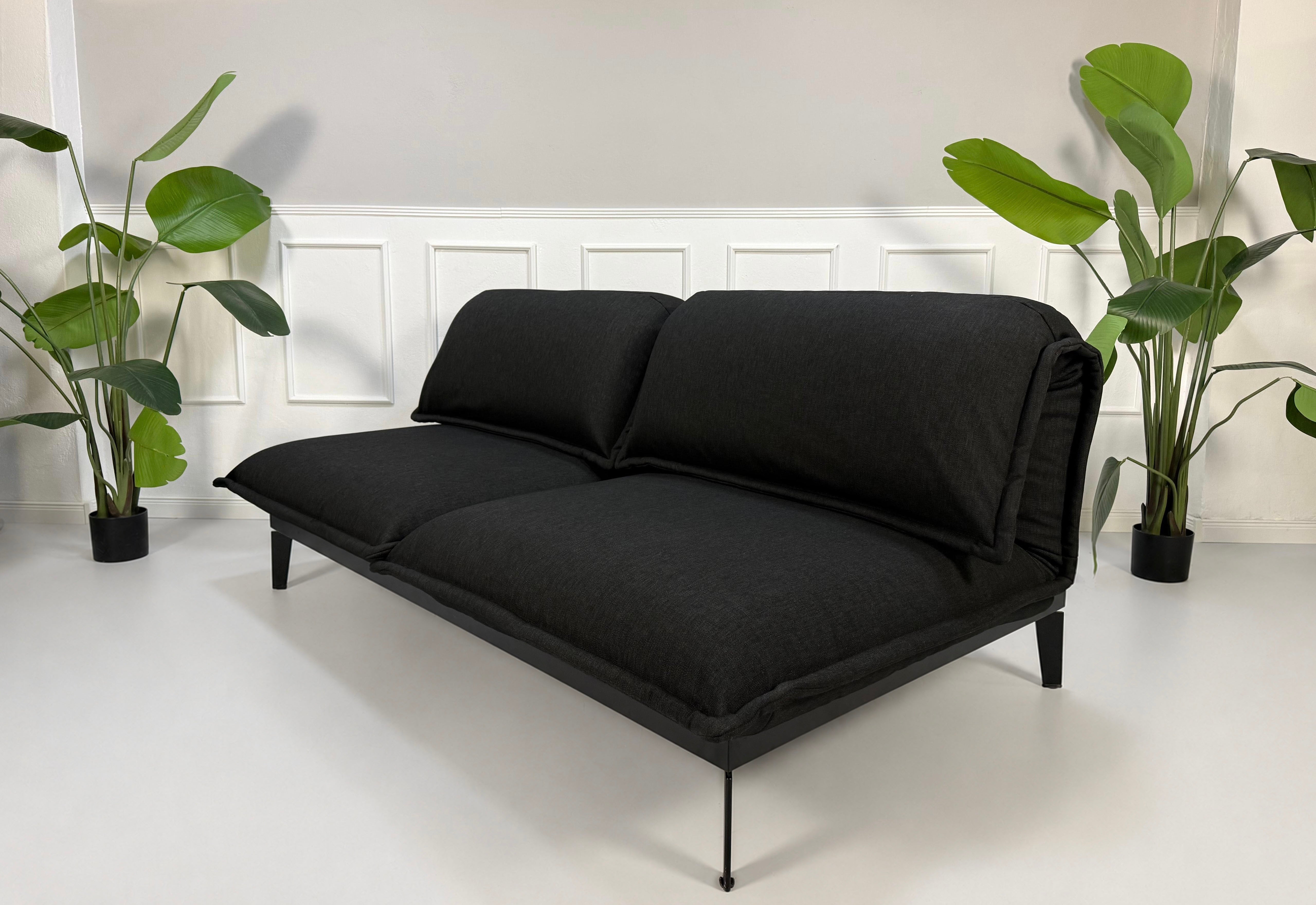 Gebrauchtes schwarzes Rolf Benz Nova Designer Stoff Sofa vor einer Wand, stilvoll und modern eingerichtet.