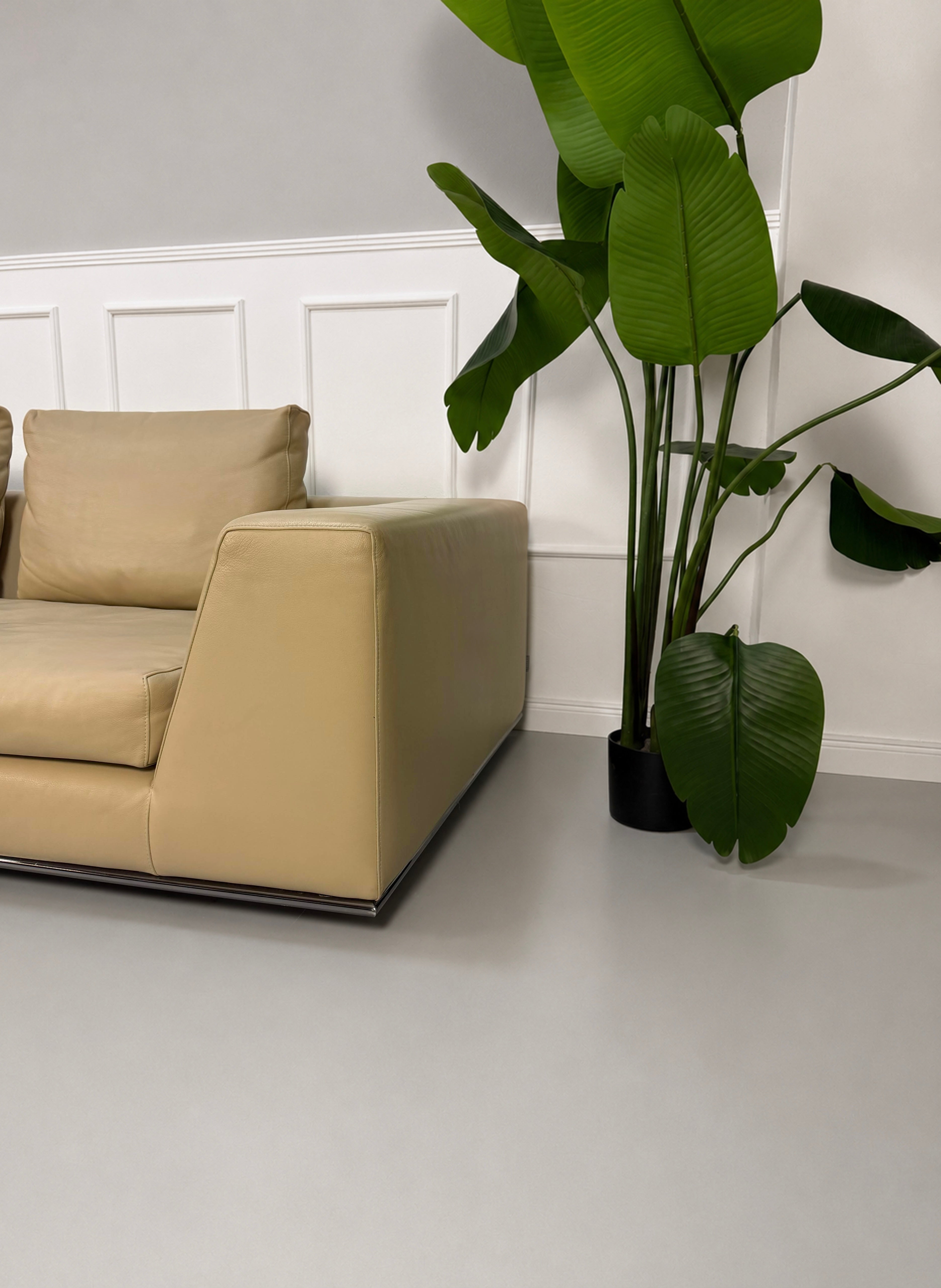Gebrauchtes beiges Minotti Hamilton Designer Leder Sofa vor einer Wand, stilvoll und modern eingerichtet.