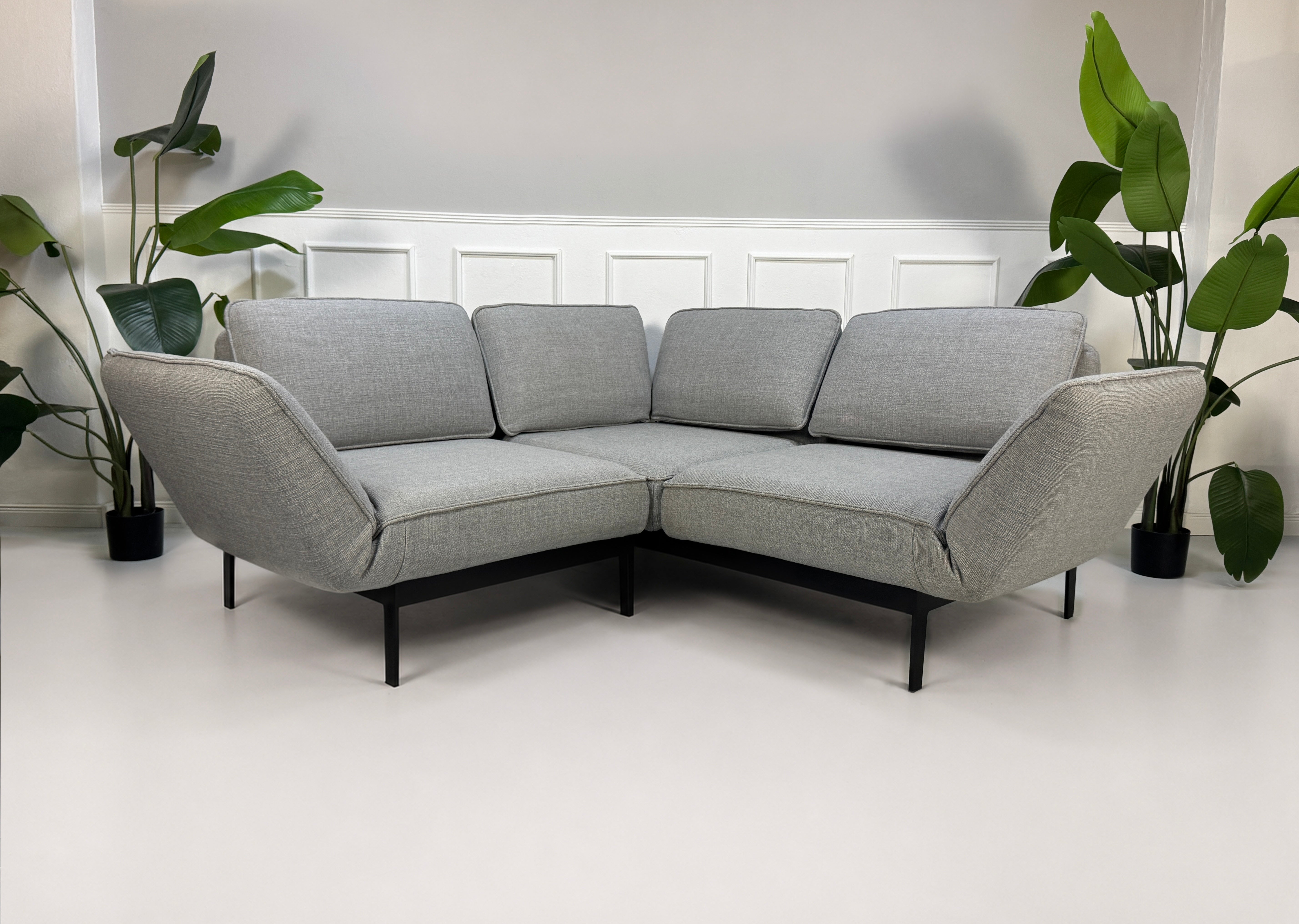 Gebrauchtes graues Rolf Benz Mera Designer Stoff Sofa vor einer Wand, stilvoll und modern eingerichtet.
