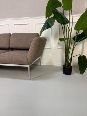 Gebrauchtes graues Brühl Roro Designer Stoff Ecksofa vor einer Wand, stilvoll und modern eingerichtet.