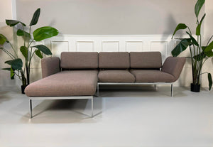 Gebrauchtes graues Brühl Roro Designer Stoff Ecksofa vor einer Wand, stilvoll und modern eingerichtet.